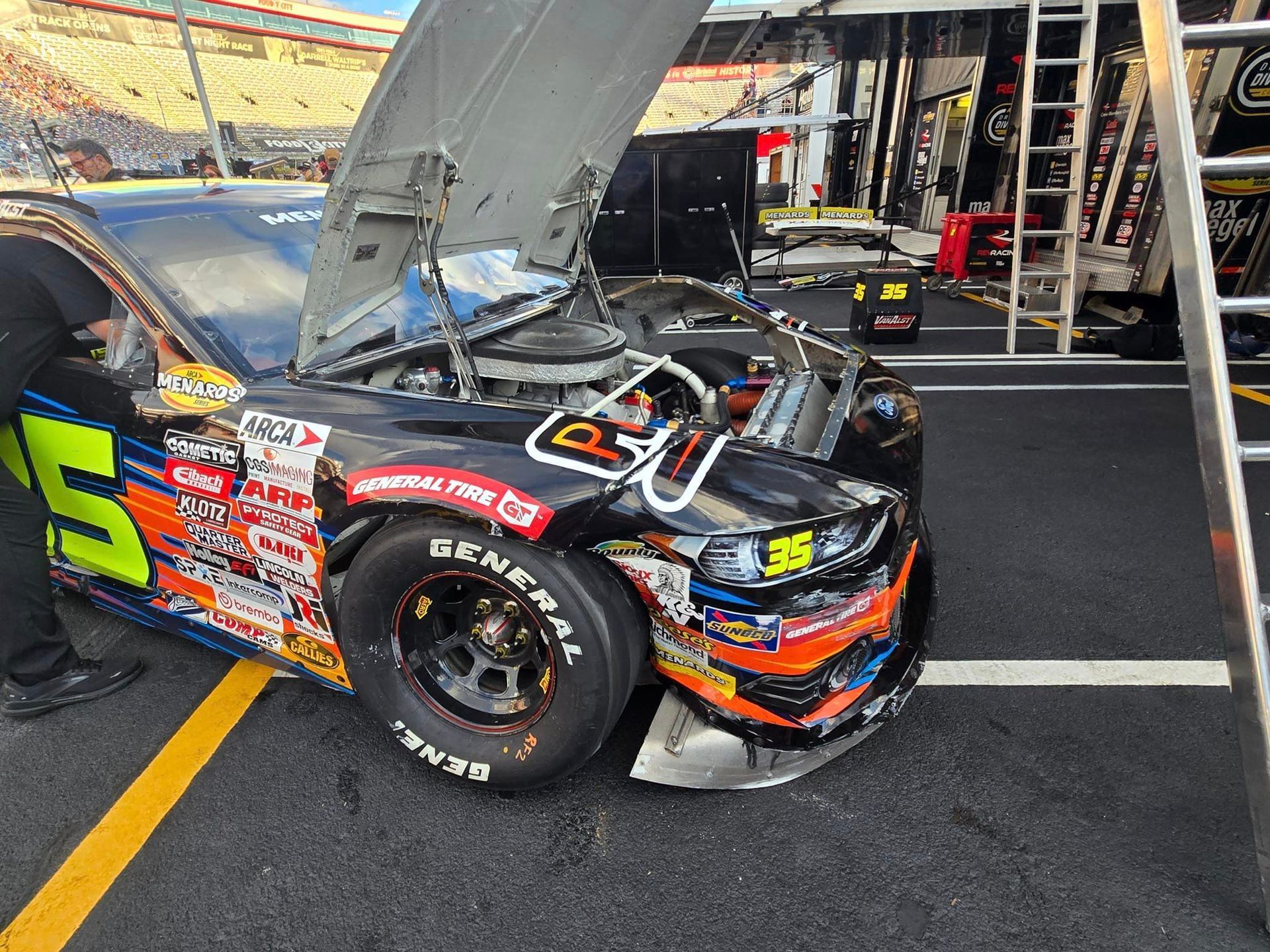 A race car is parked in a garage with the hood open