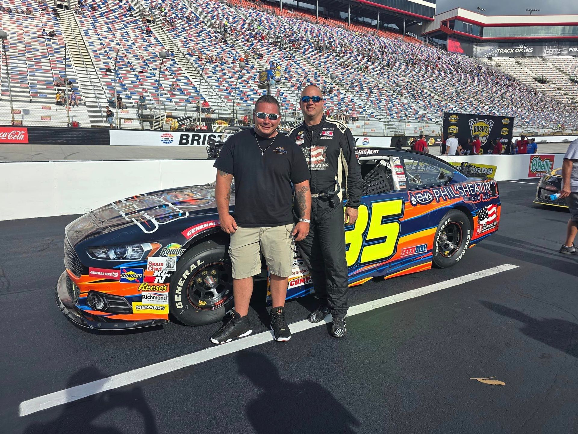 Two men are standing next to a race car with the number 35 on it.