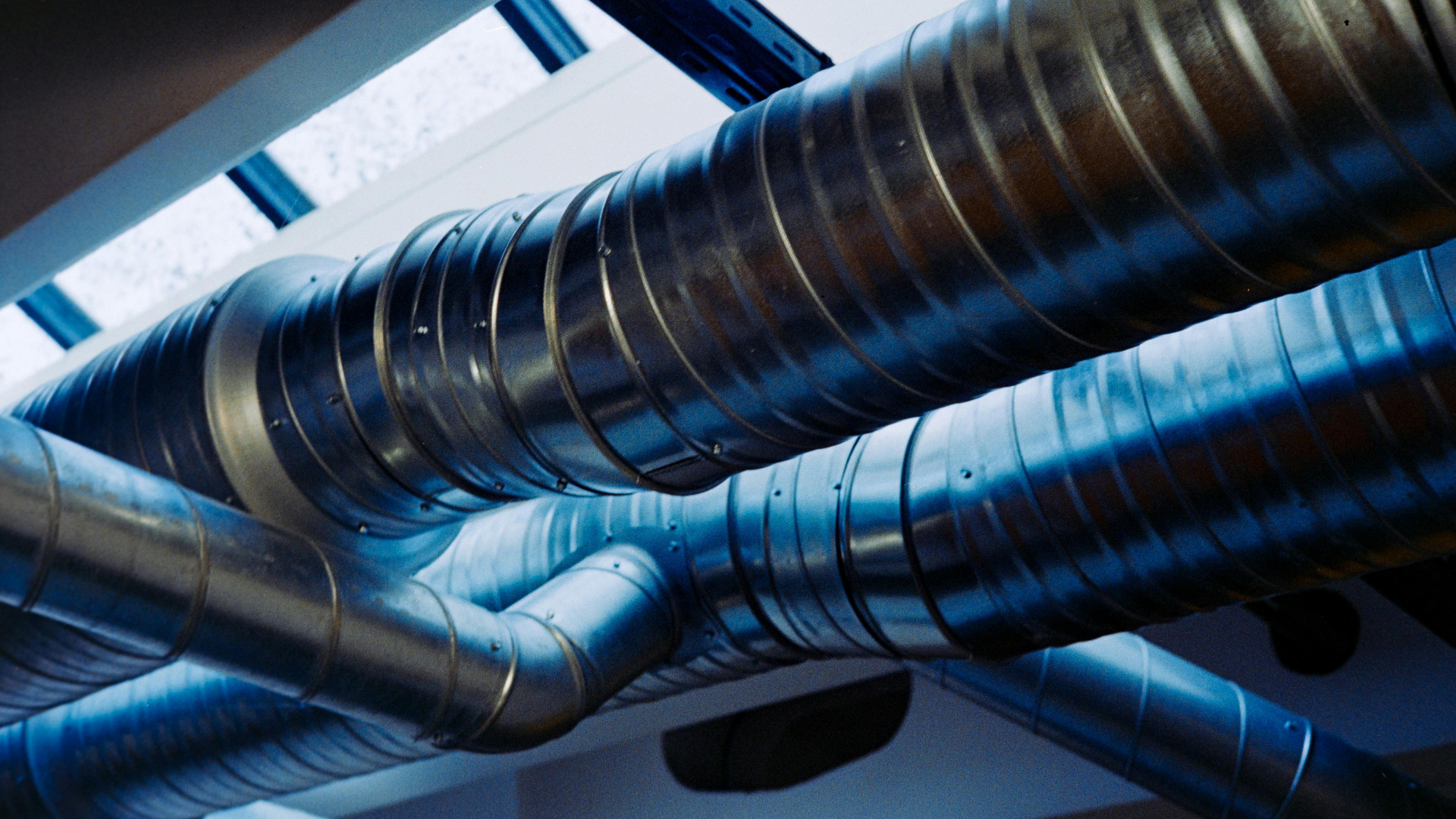 A bunch of metal pipes are hanging from the ceiling of a building.