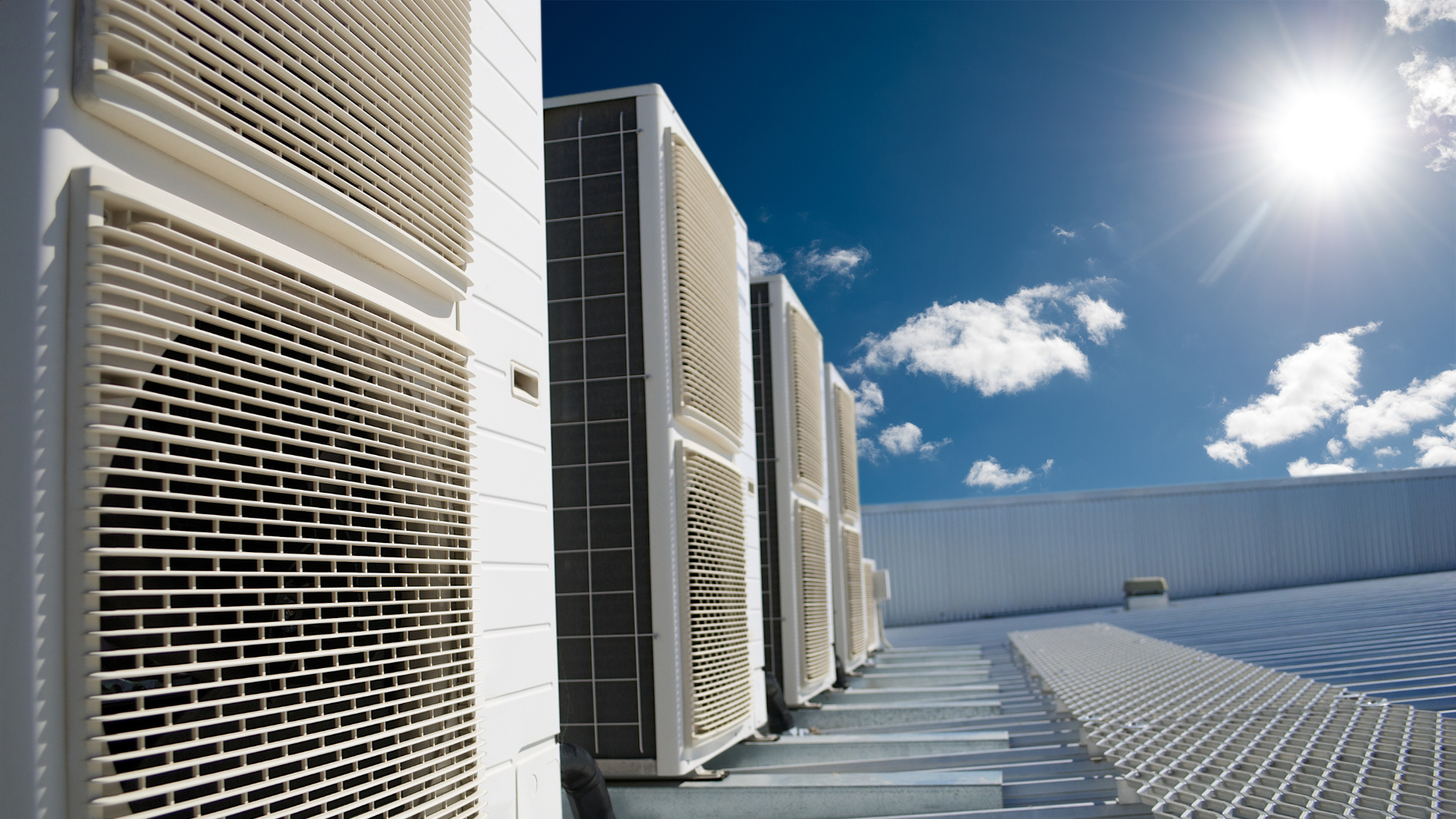 A row of air conditioners are lined up on the roof of a building.