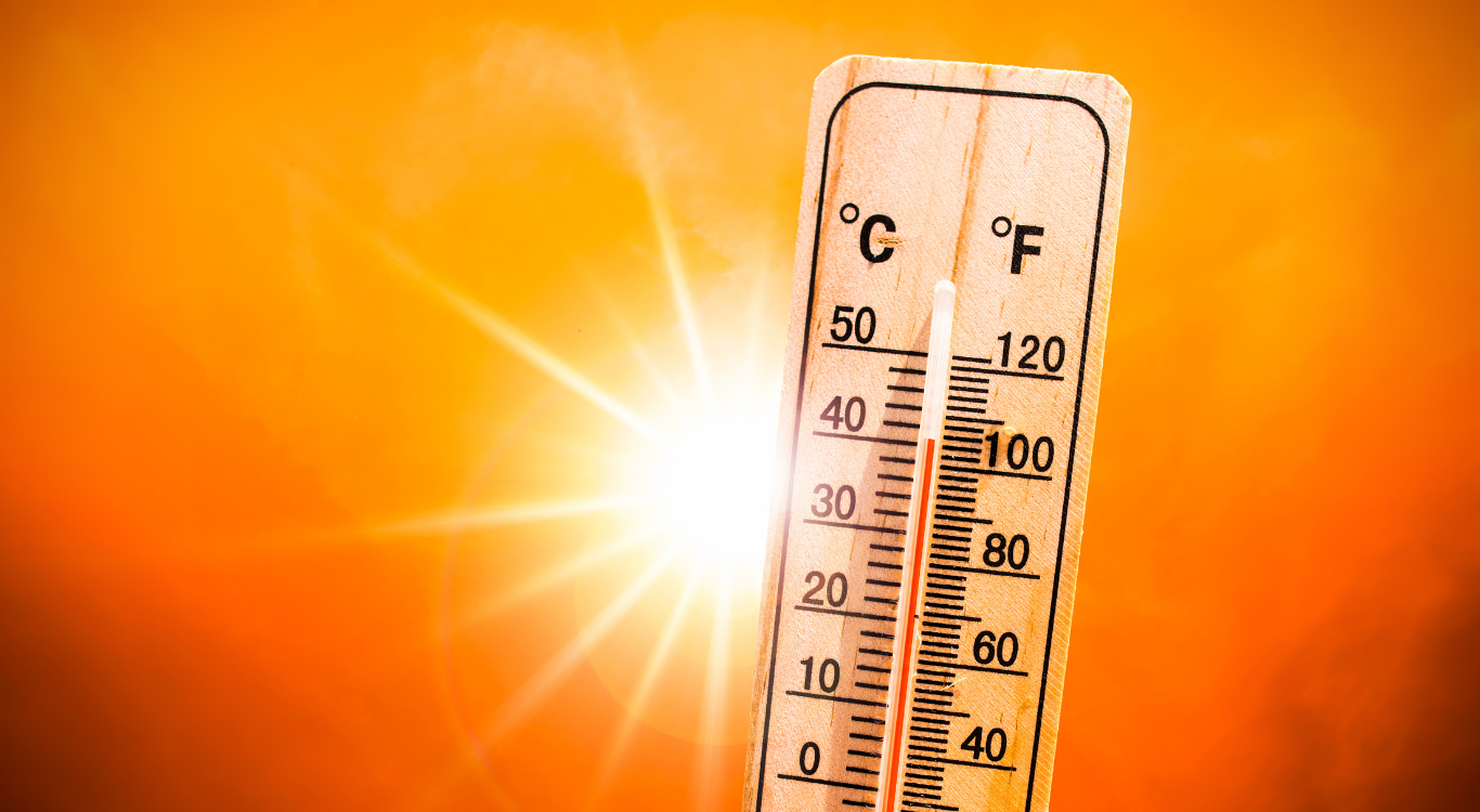 A wooden thermometer is sitting in front of a bright orange background.