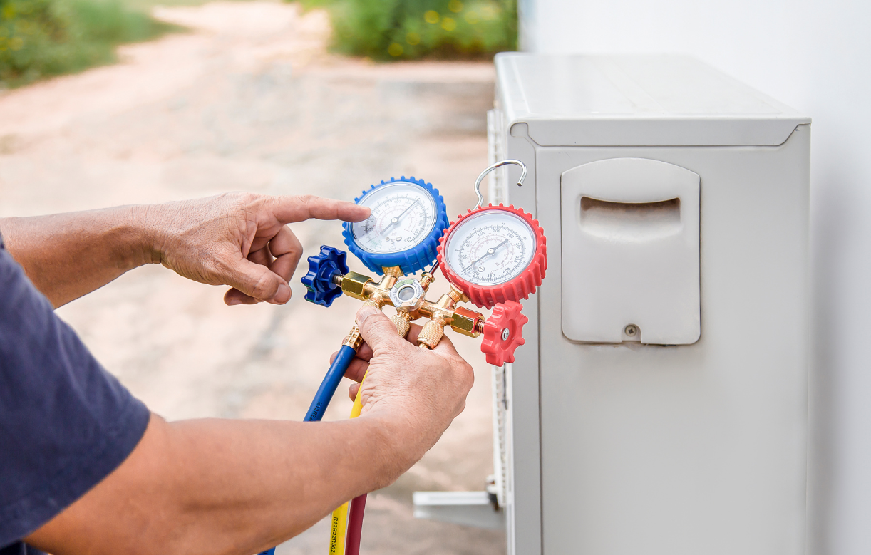 Person using pressure gauges to service an air conditioning unit.