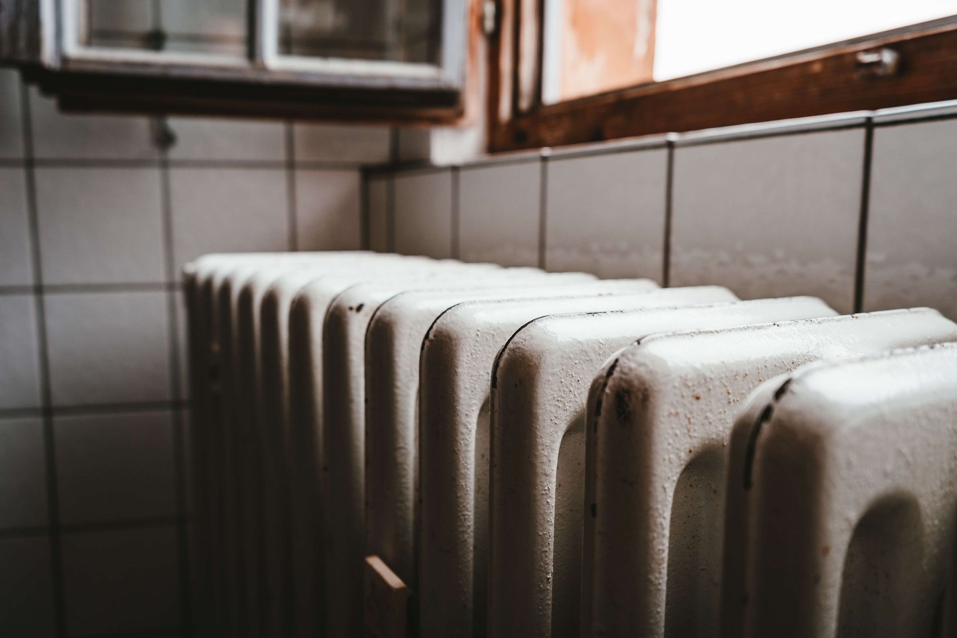 A radiator is sitting next to a window in a bathroom.