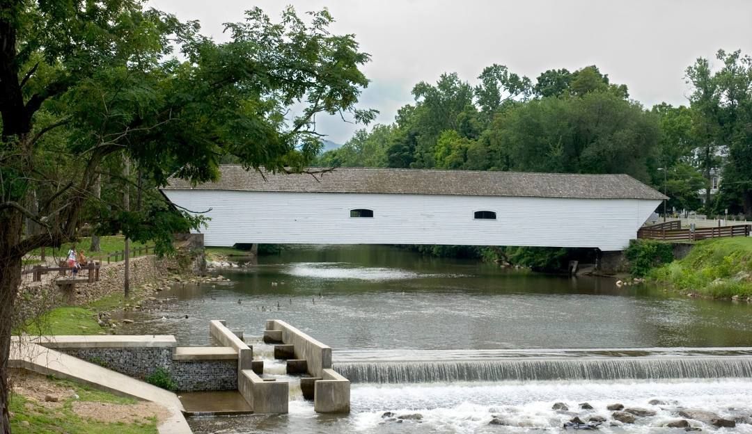 The white covered bridge over a river with a waterfall in Elizabethton Tennessee