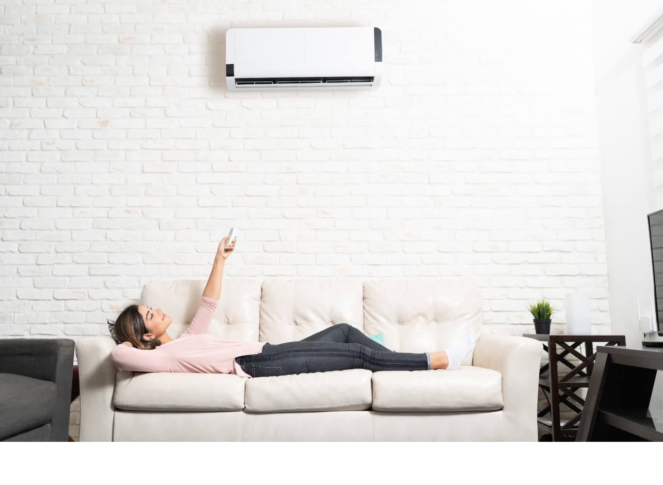 A woman is laying on a couch holding a remote control.