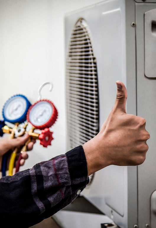 A person is giving a thumbs up in front of an air conditioner.