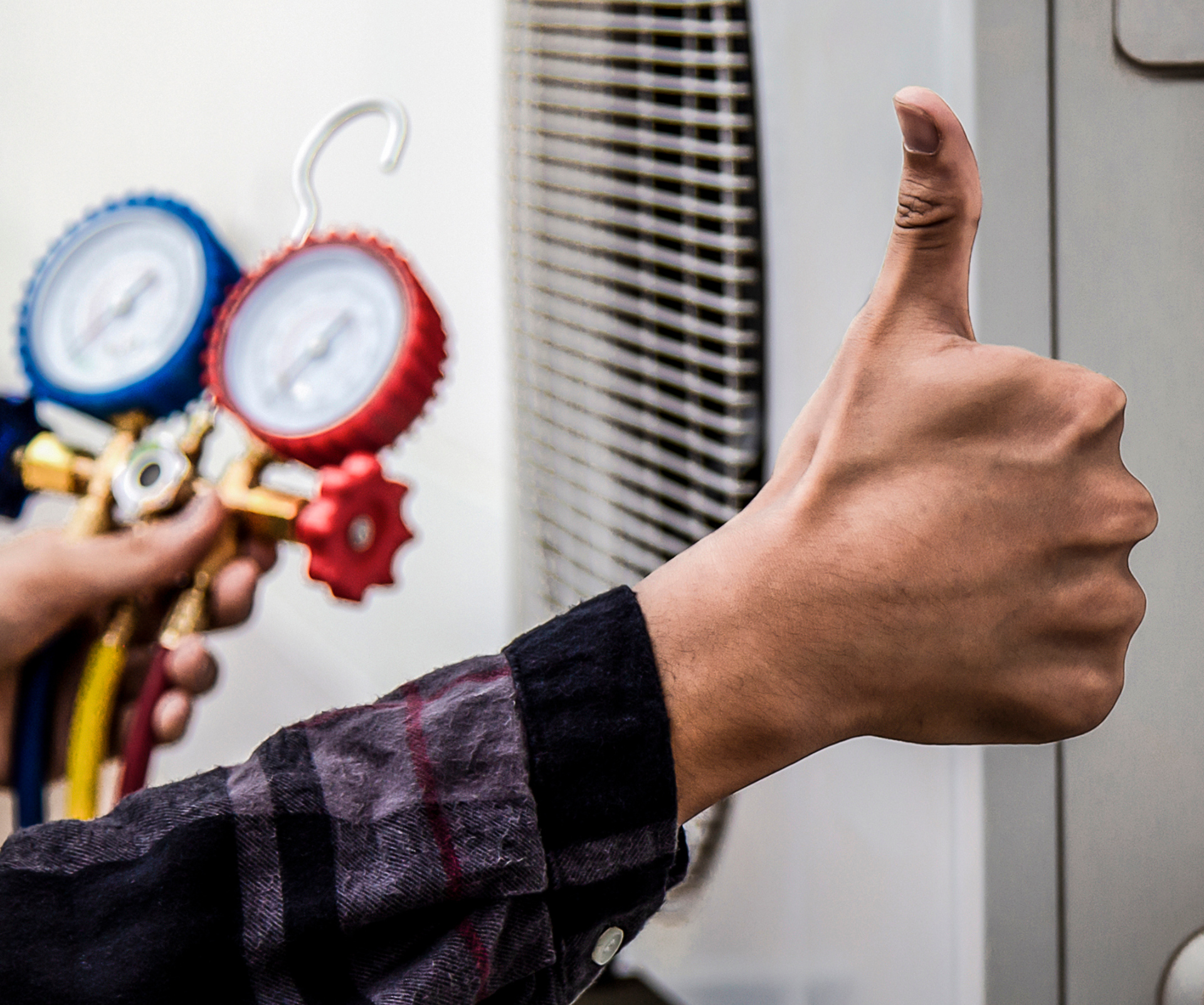 A man is working on an air conditioner on the roof of a building.