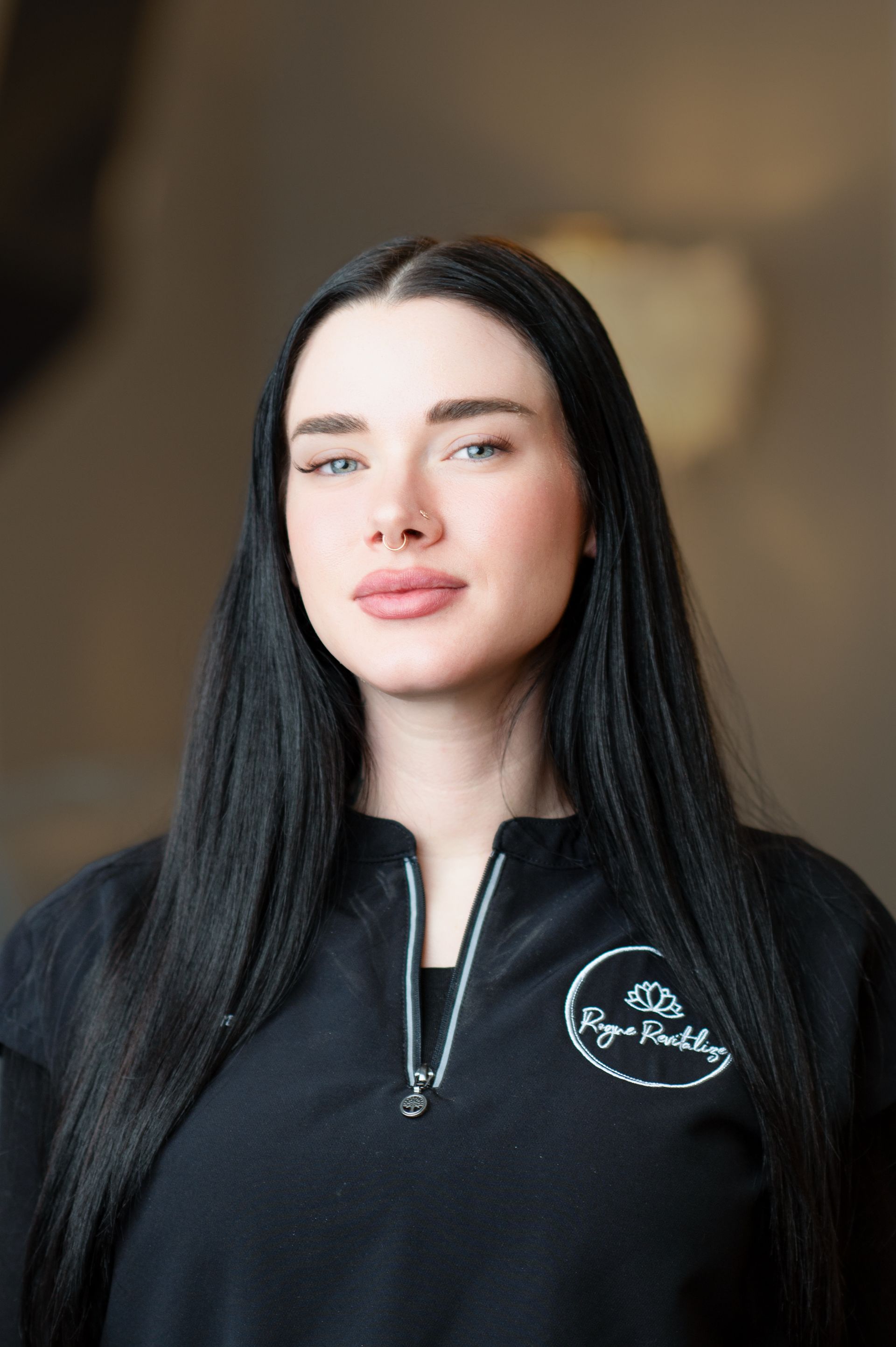A woman with long black hair is wearing a black shirt and smiling.