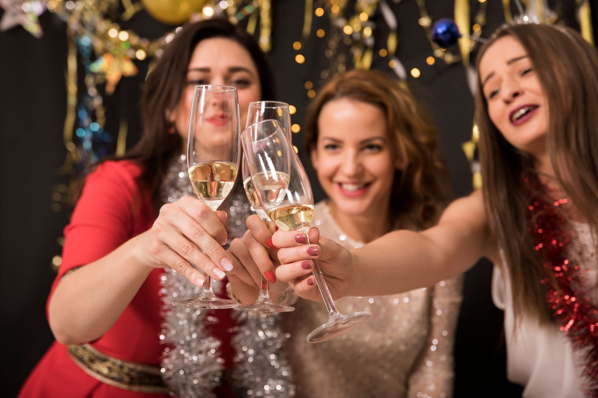 Three women are toasting with champagne glasses at a party.