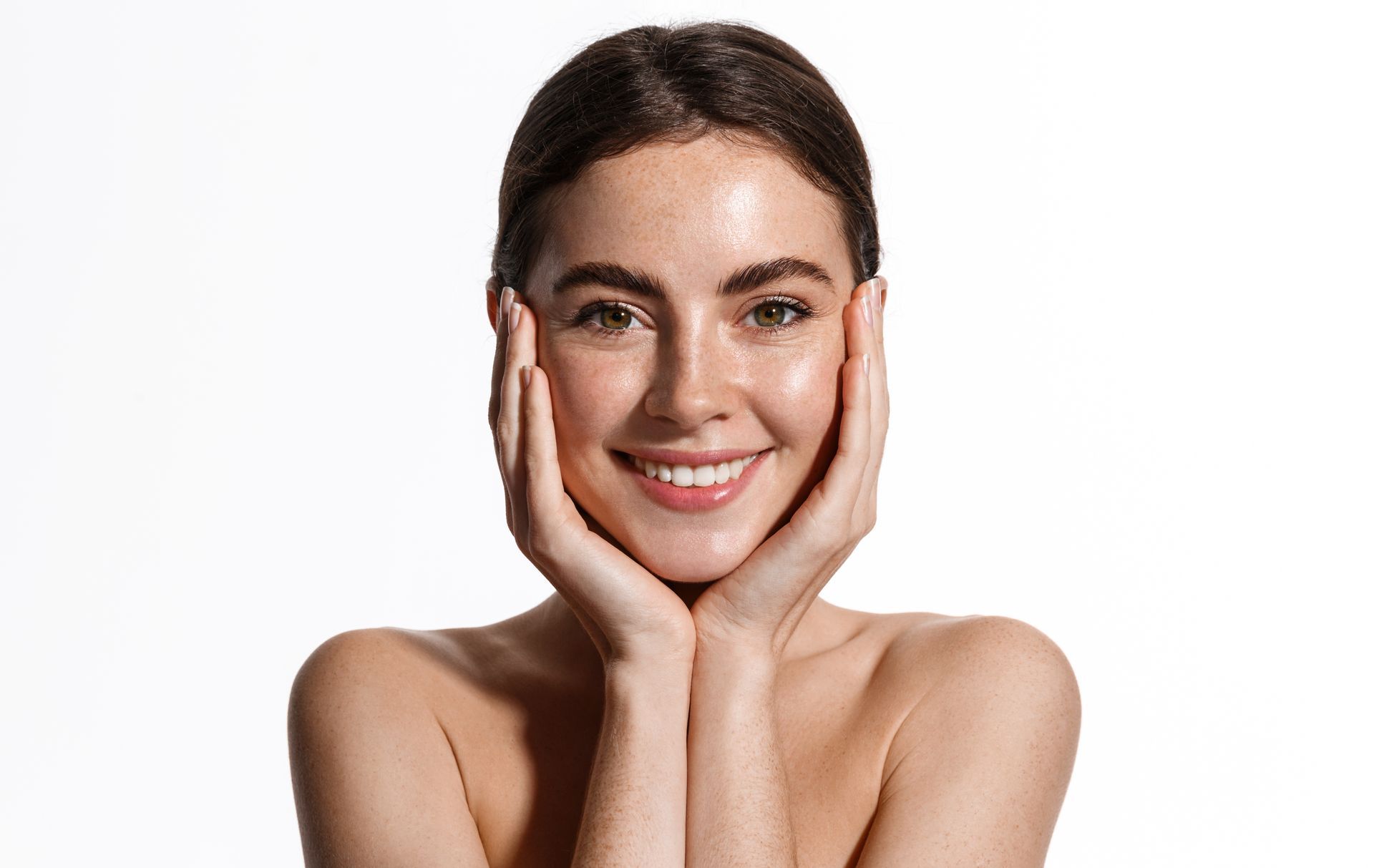 Smiling woman with hands on cheeks against a white background