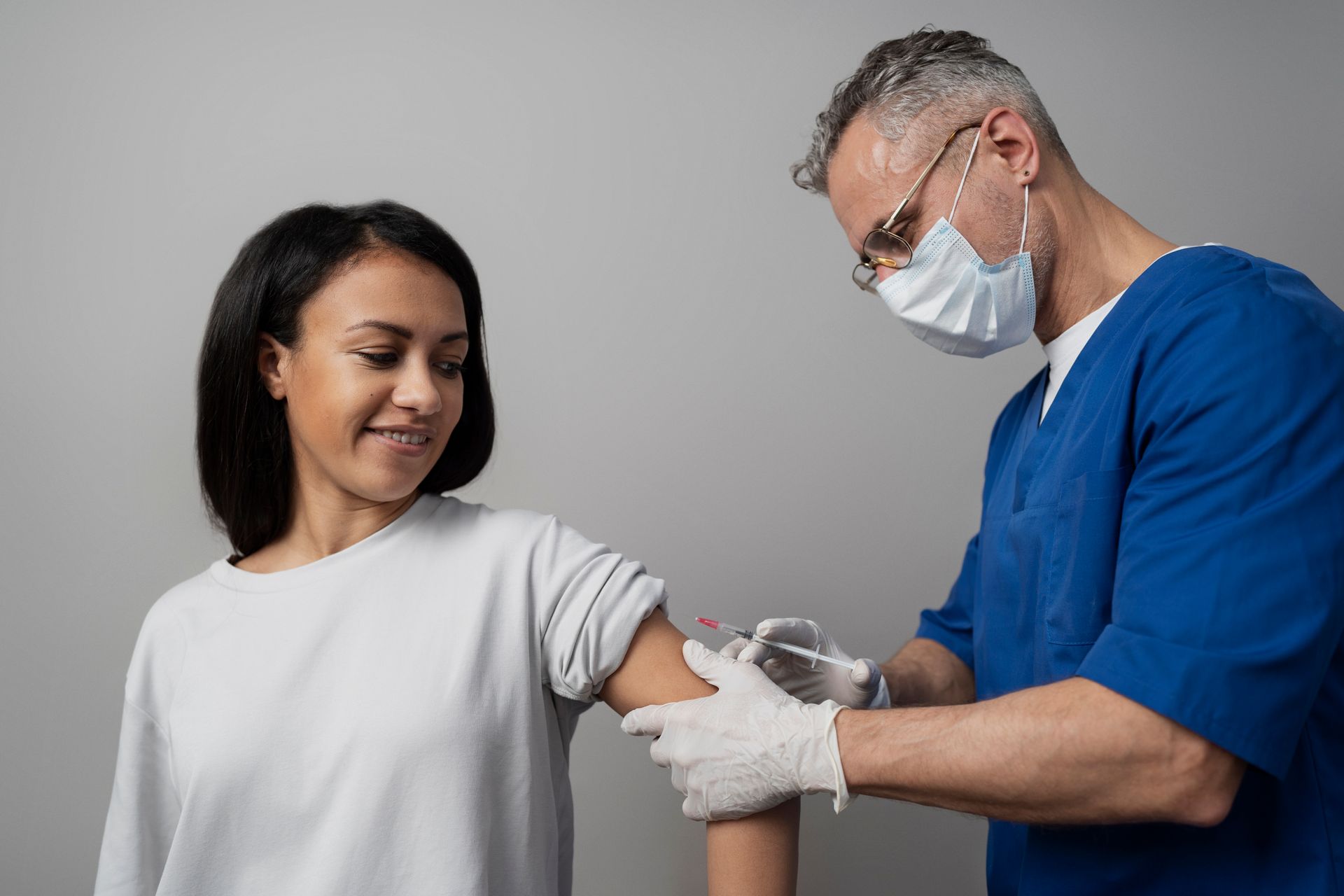 A doctor is giving a woman an injection in her arm.