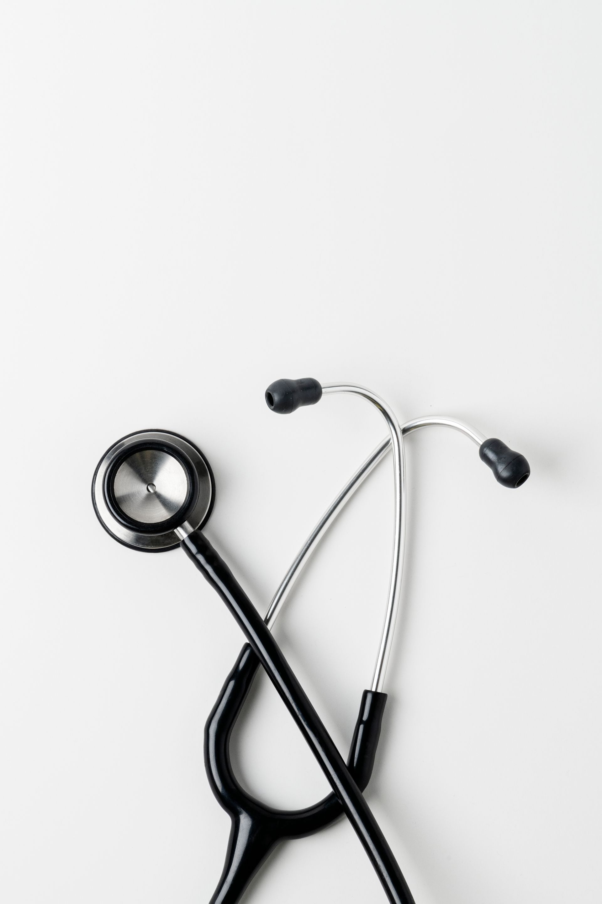 Two stethoscopes are crossed over each other on a white surface.