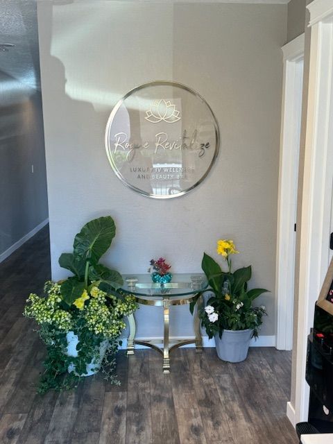 A round mirror hangs on a wall above a table with potted plants.