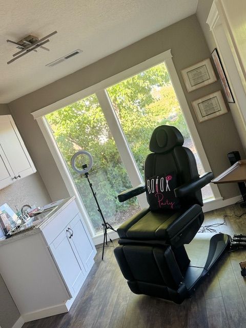 A black chair in a room with a window and a ring light