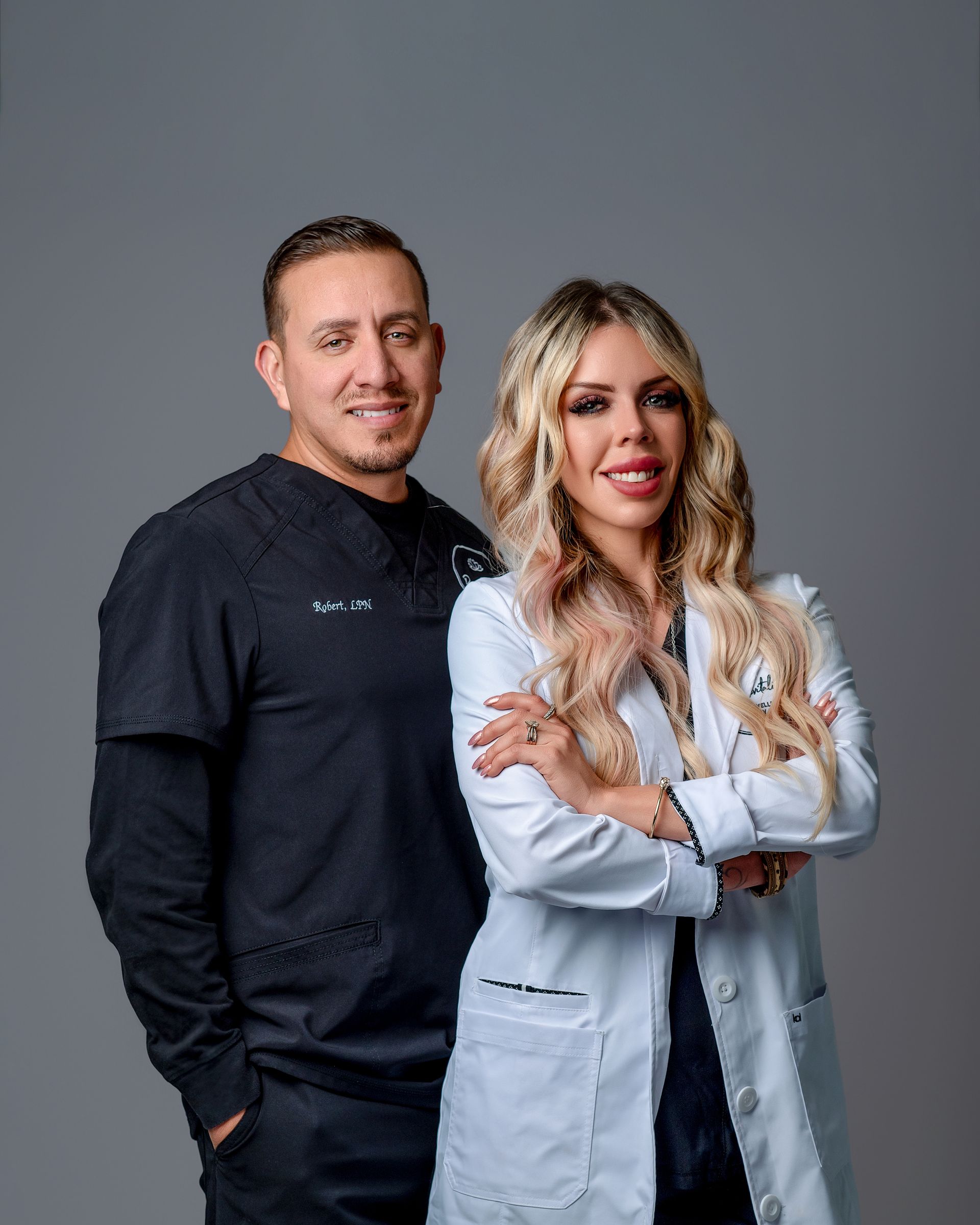 A man and a woman are standing next to each other with their arms crossed.