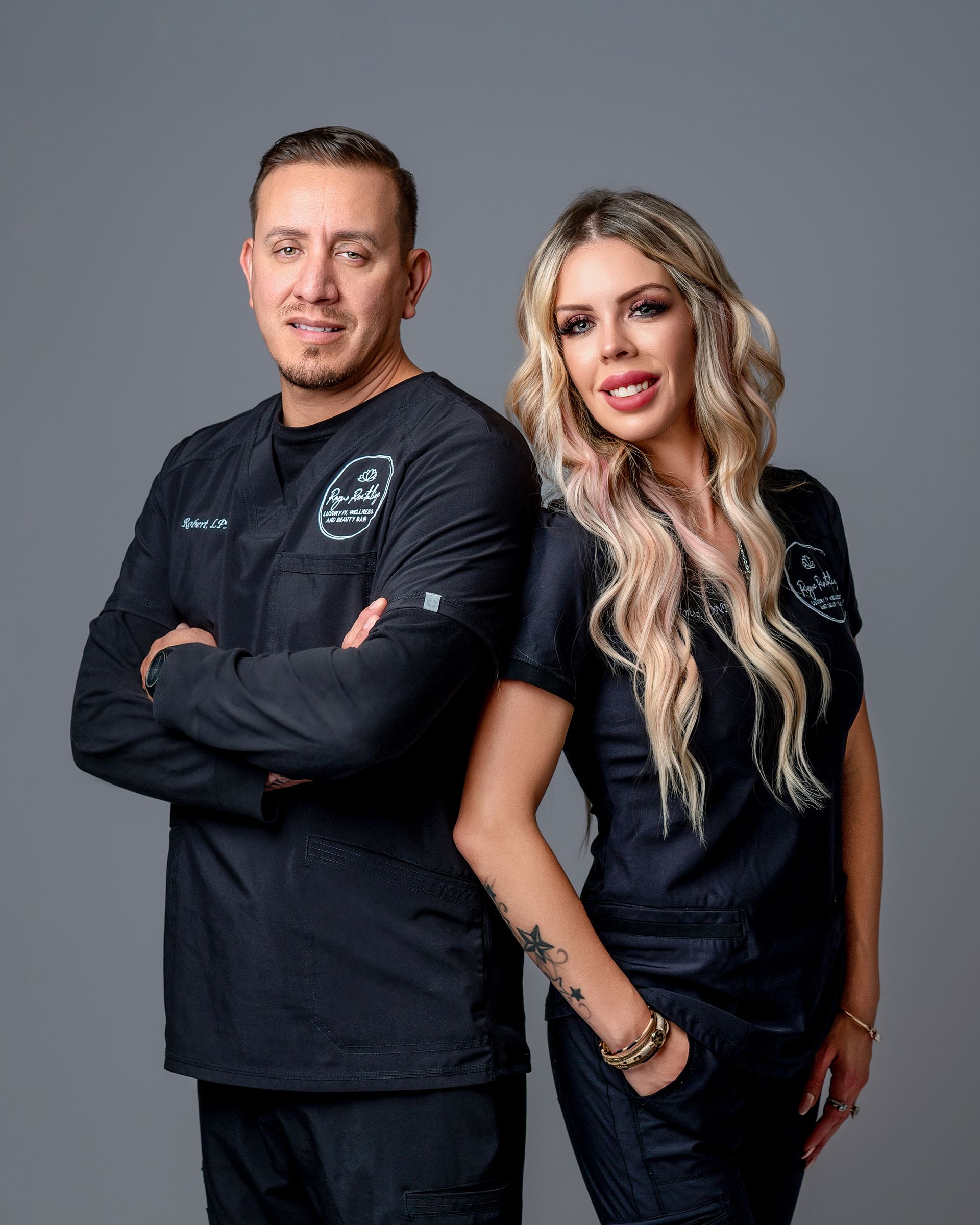 A man and a woman are standing next to each other with their arms crossed.