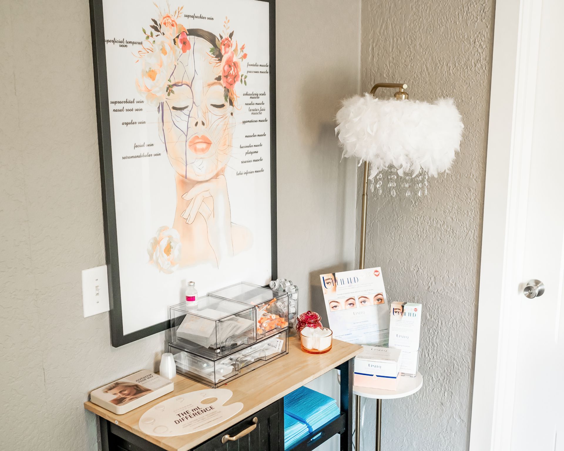There is a painting of a woman on the wall above a desk.