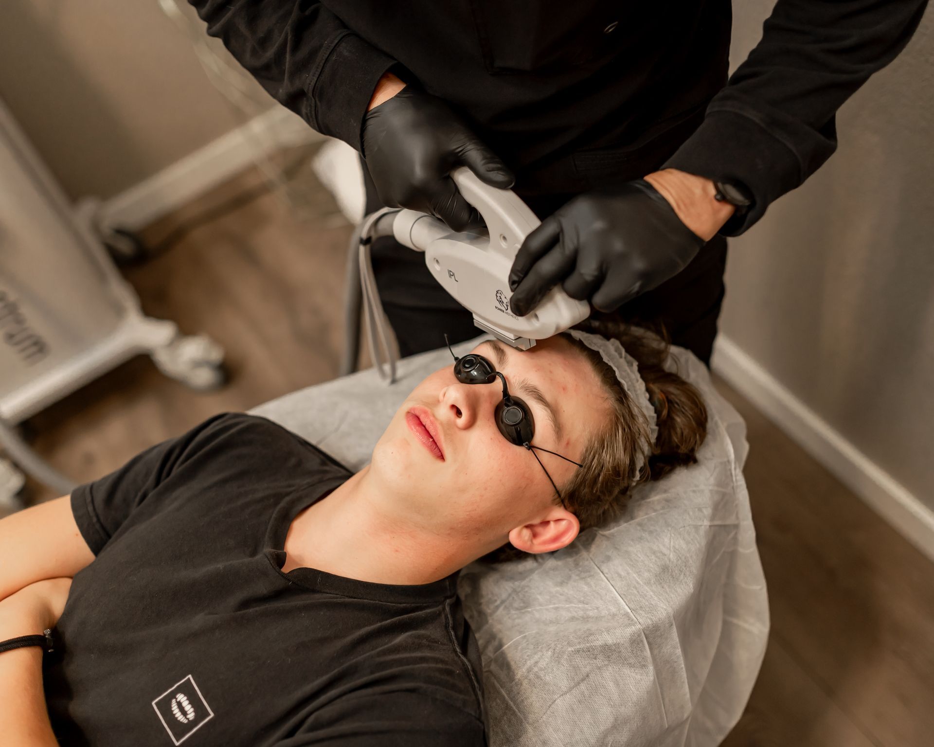 A man wearing sunglasses is getting a laser treatment on his face.