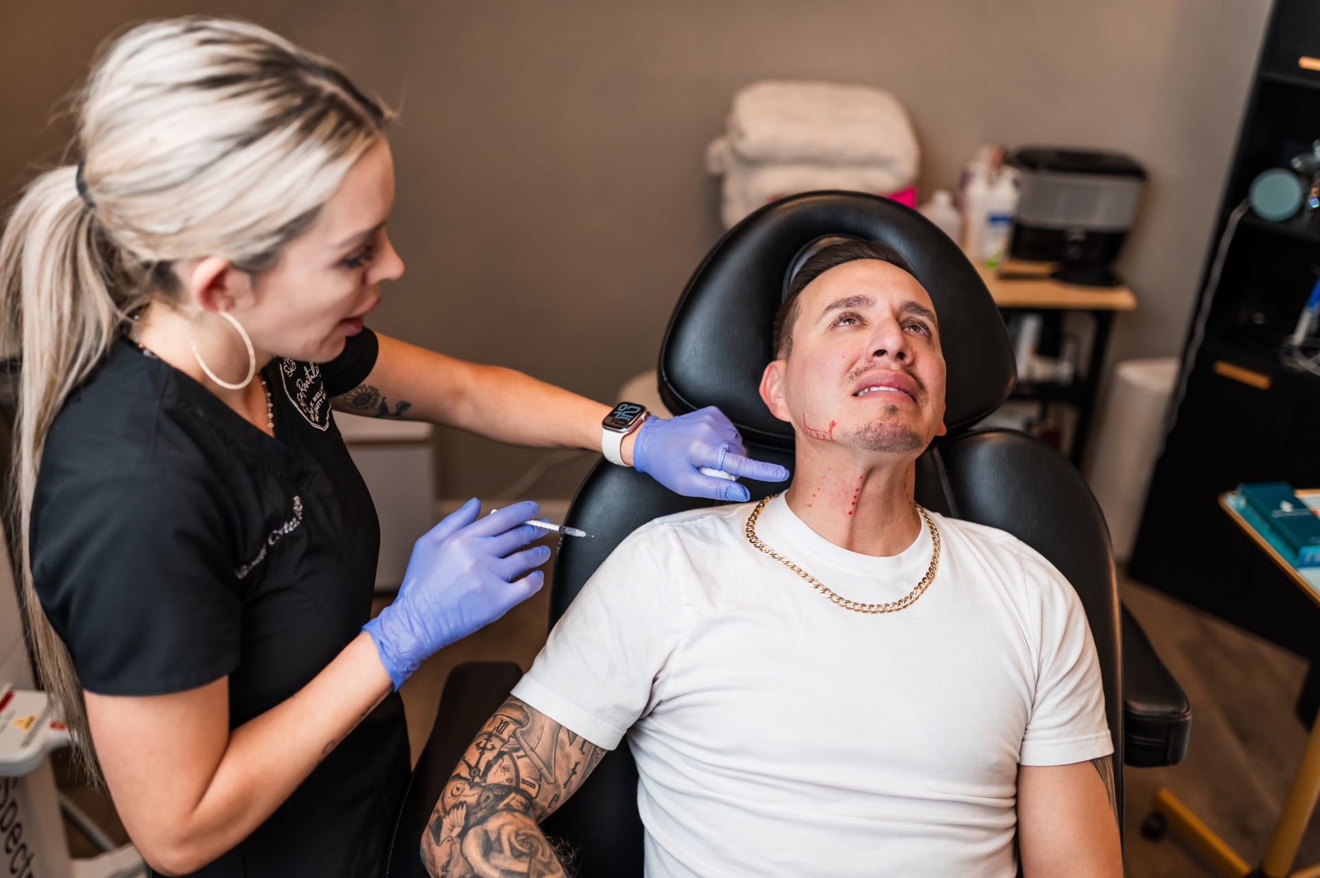 A person receiving injections in their neck from a medical professional. Interior room setting.