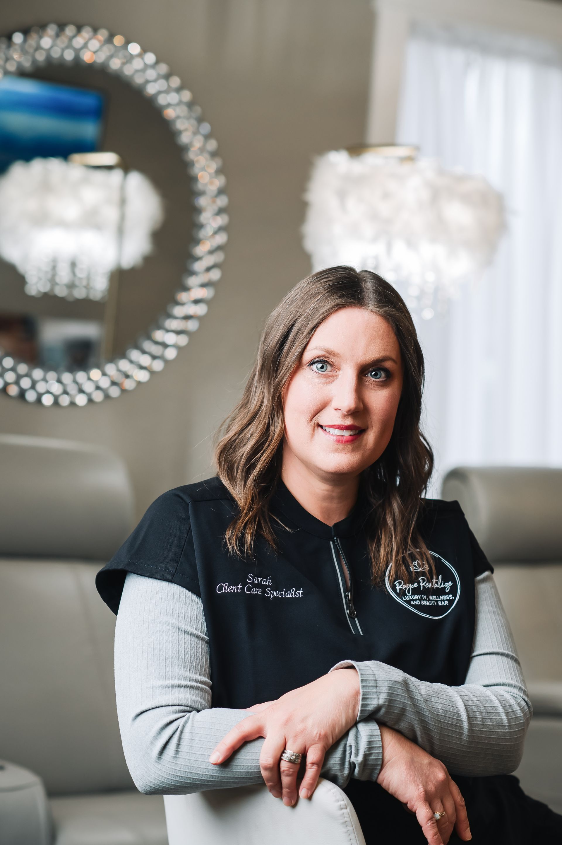 A woman is sitting in a chair with her arms crossed in front of a mirror.