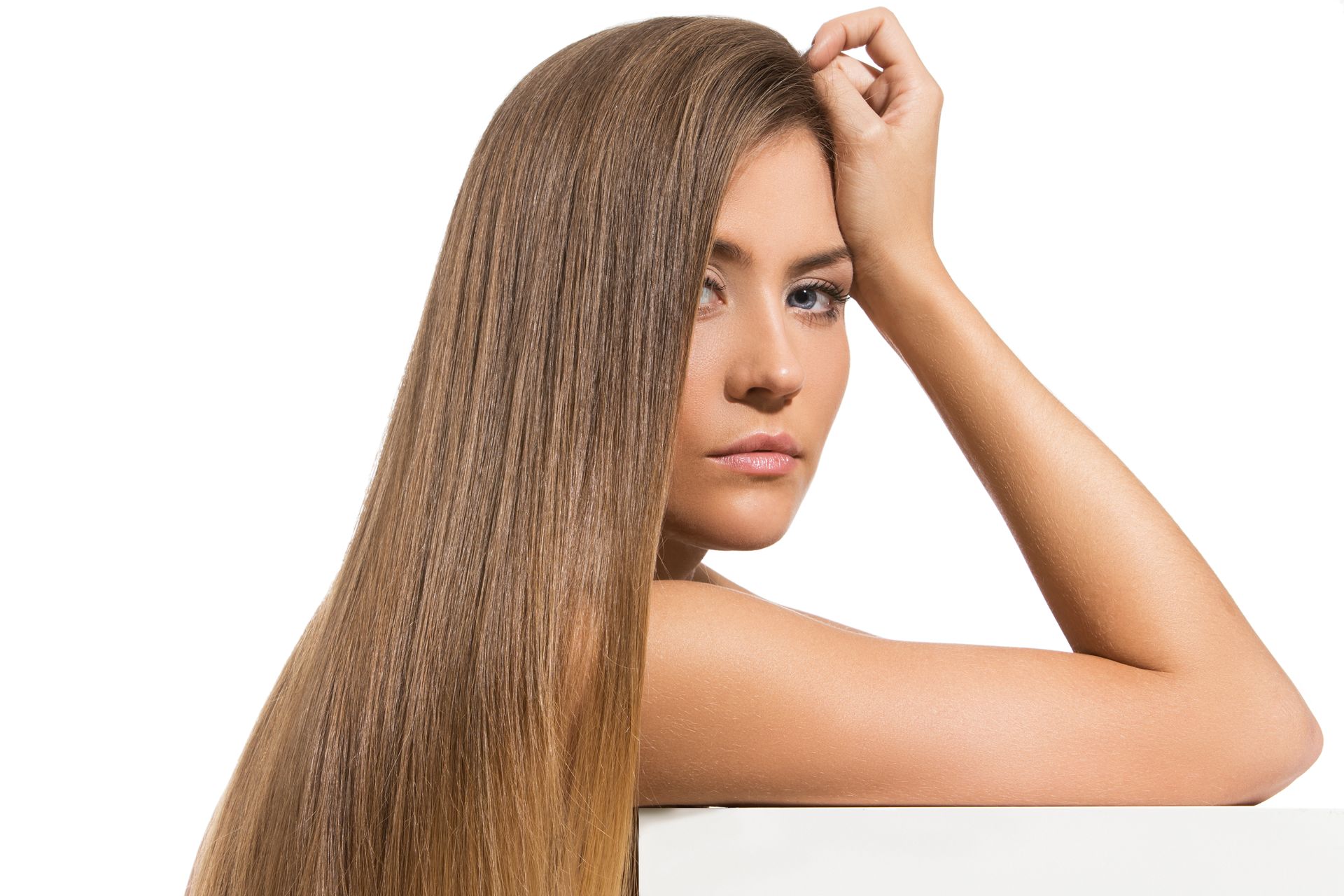 a woman with long hair is leaning against a white wall .
