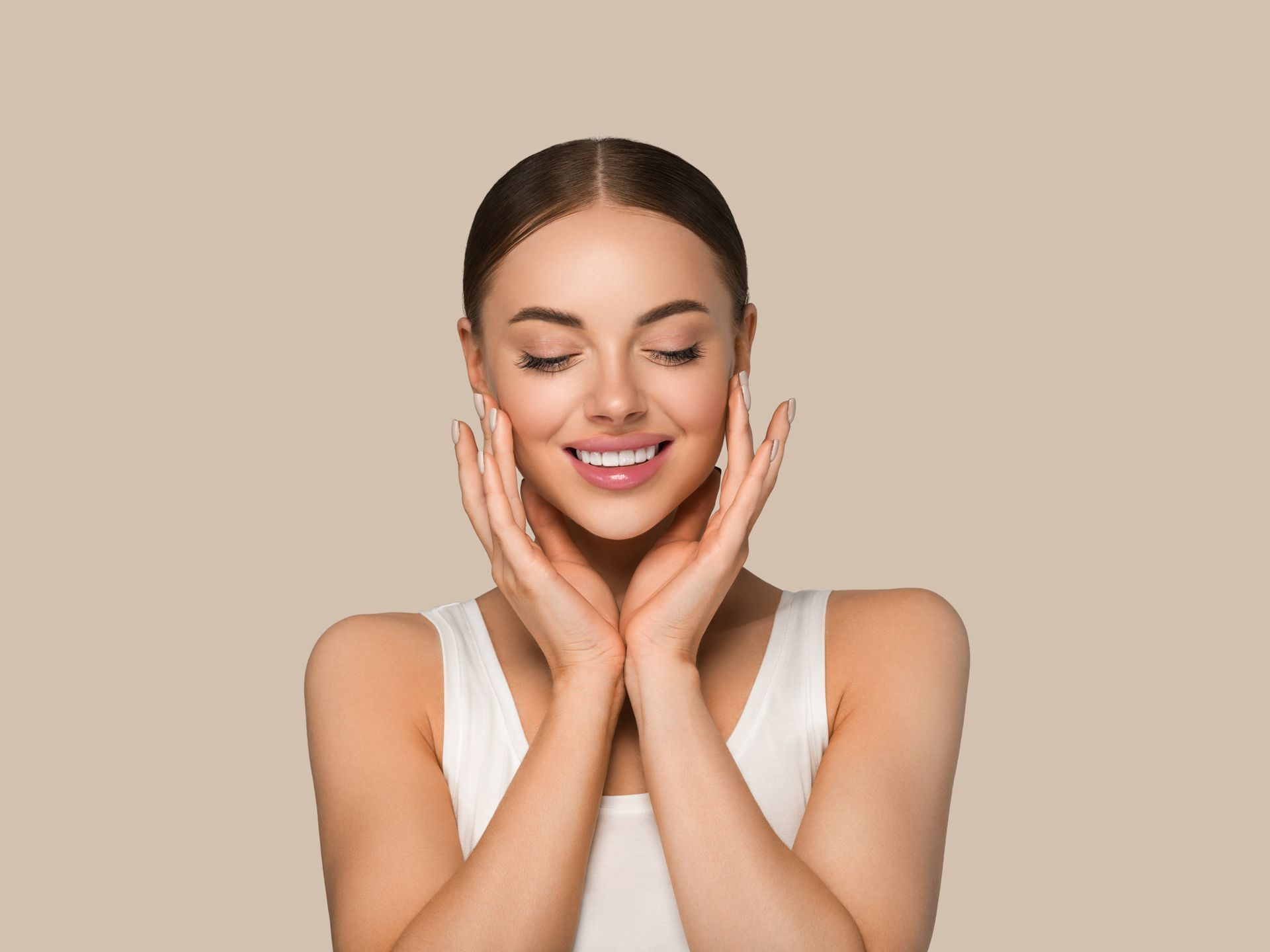 A woman is smiling and touching her face with her hands.