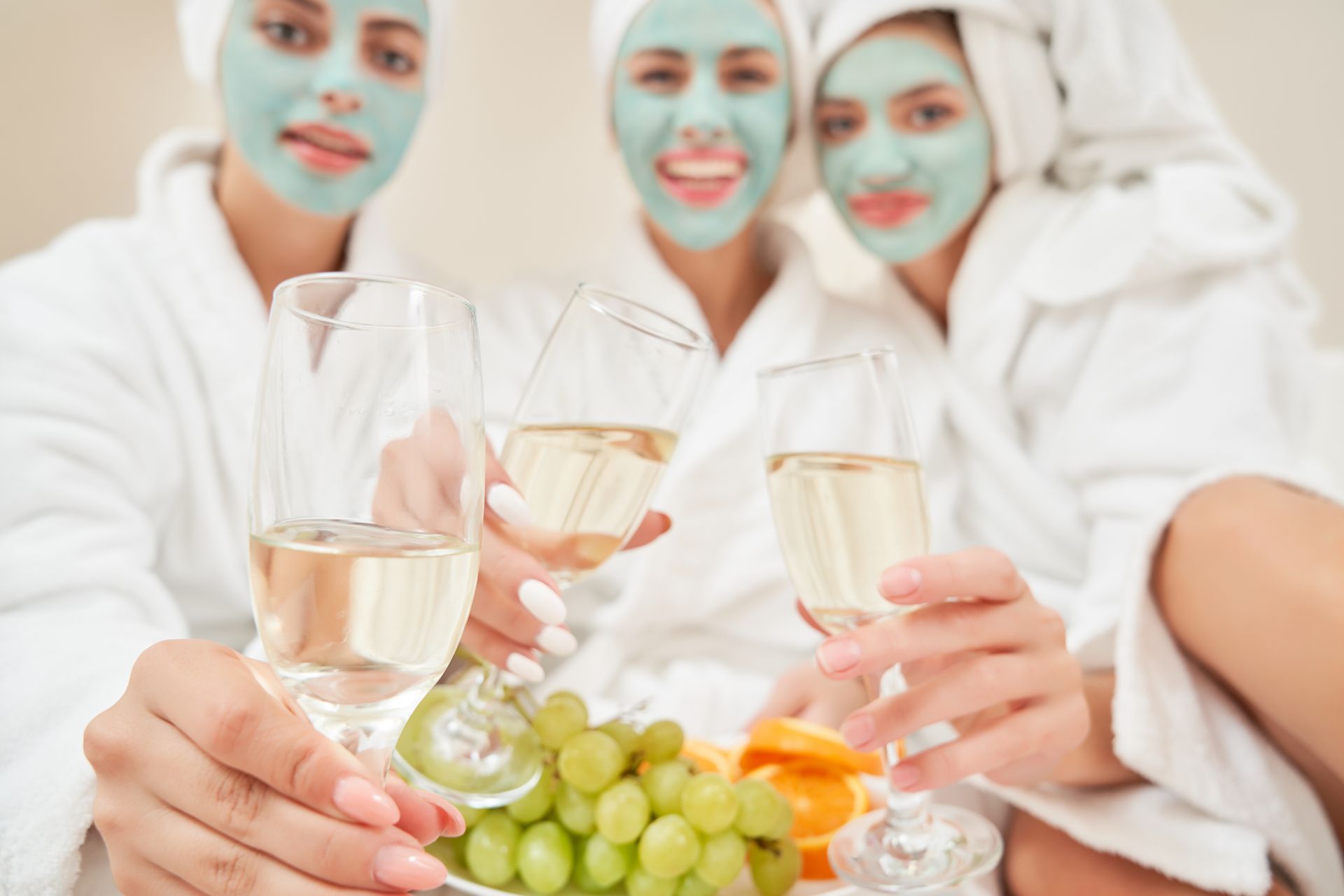 three women wearing bathrobes and towels on their heads are sitting on a bed .