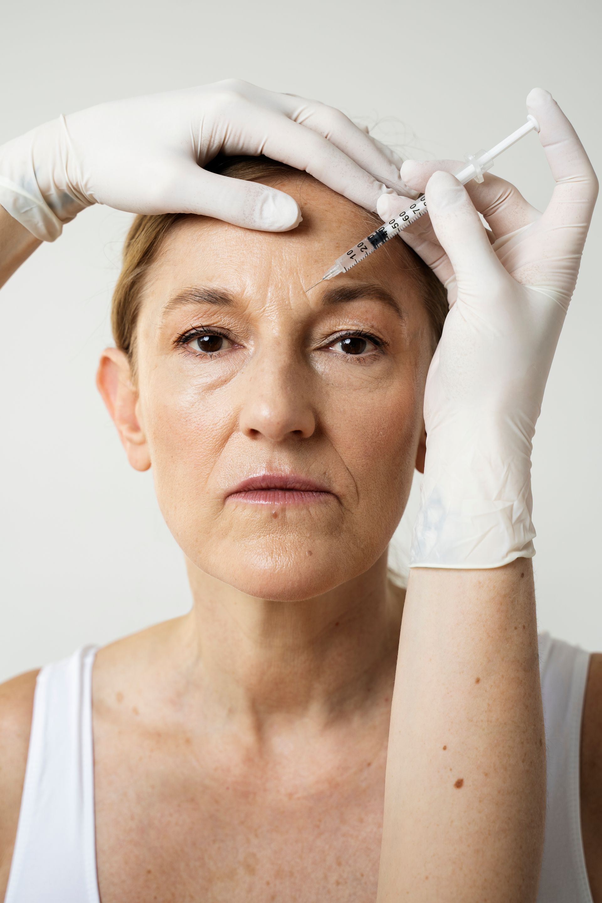 A woman is getting a botox injection on her forehead.