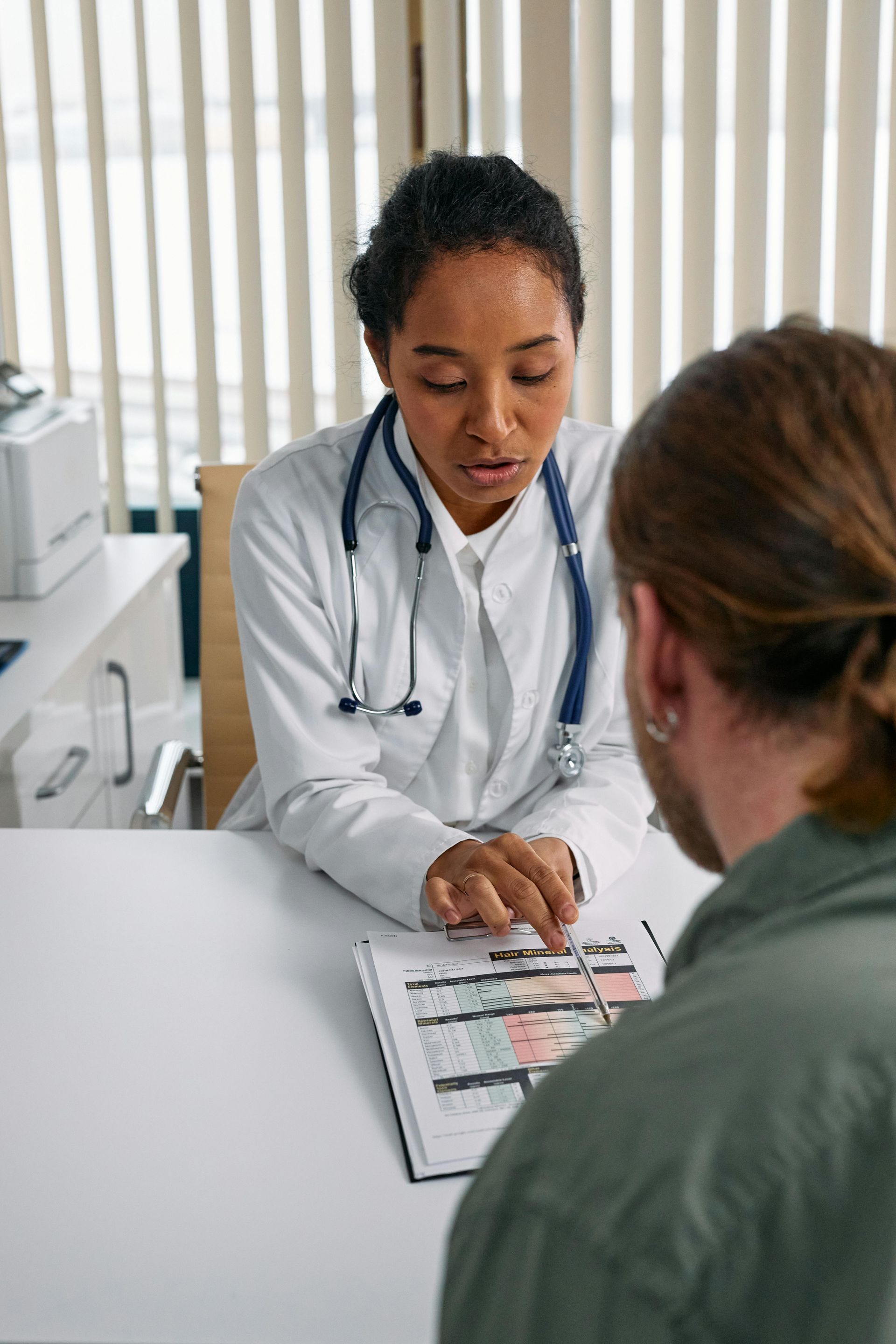 A doctor is sitting at a desk talking to a patient.