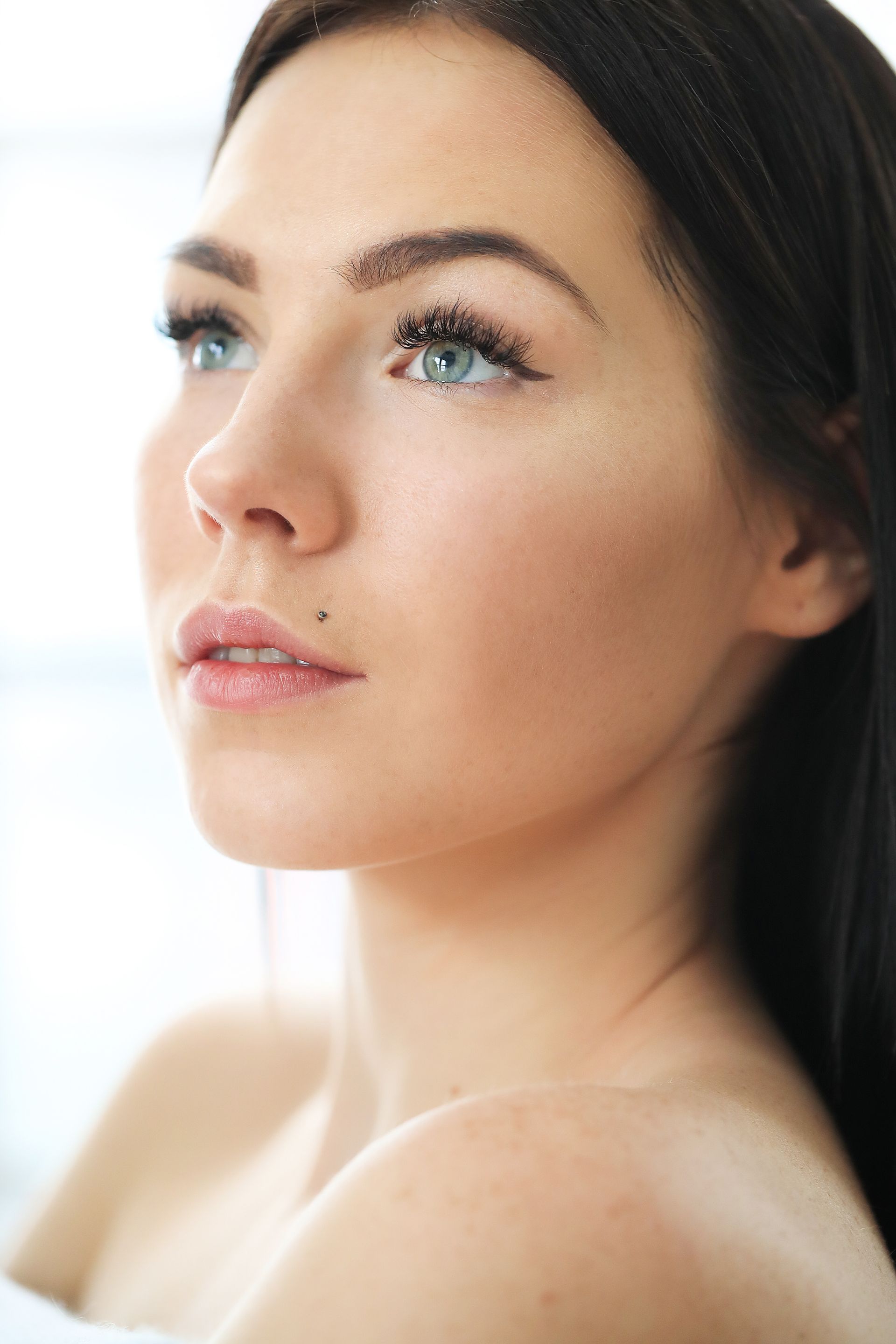 a woman with long hair is leaning against a white wall .