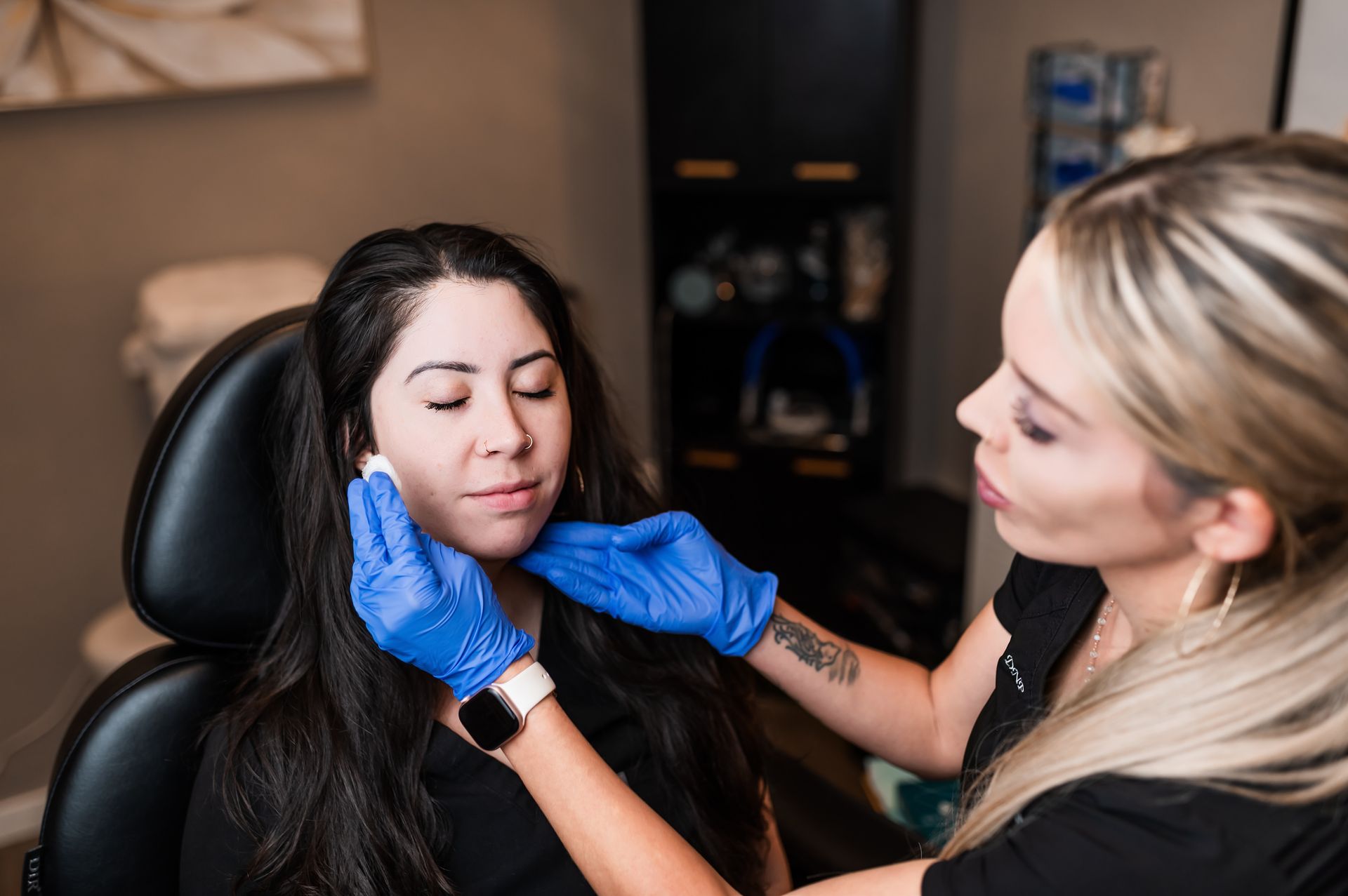 A woman is touching her face with her hands and smiling.