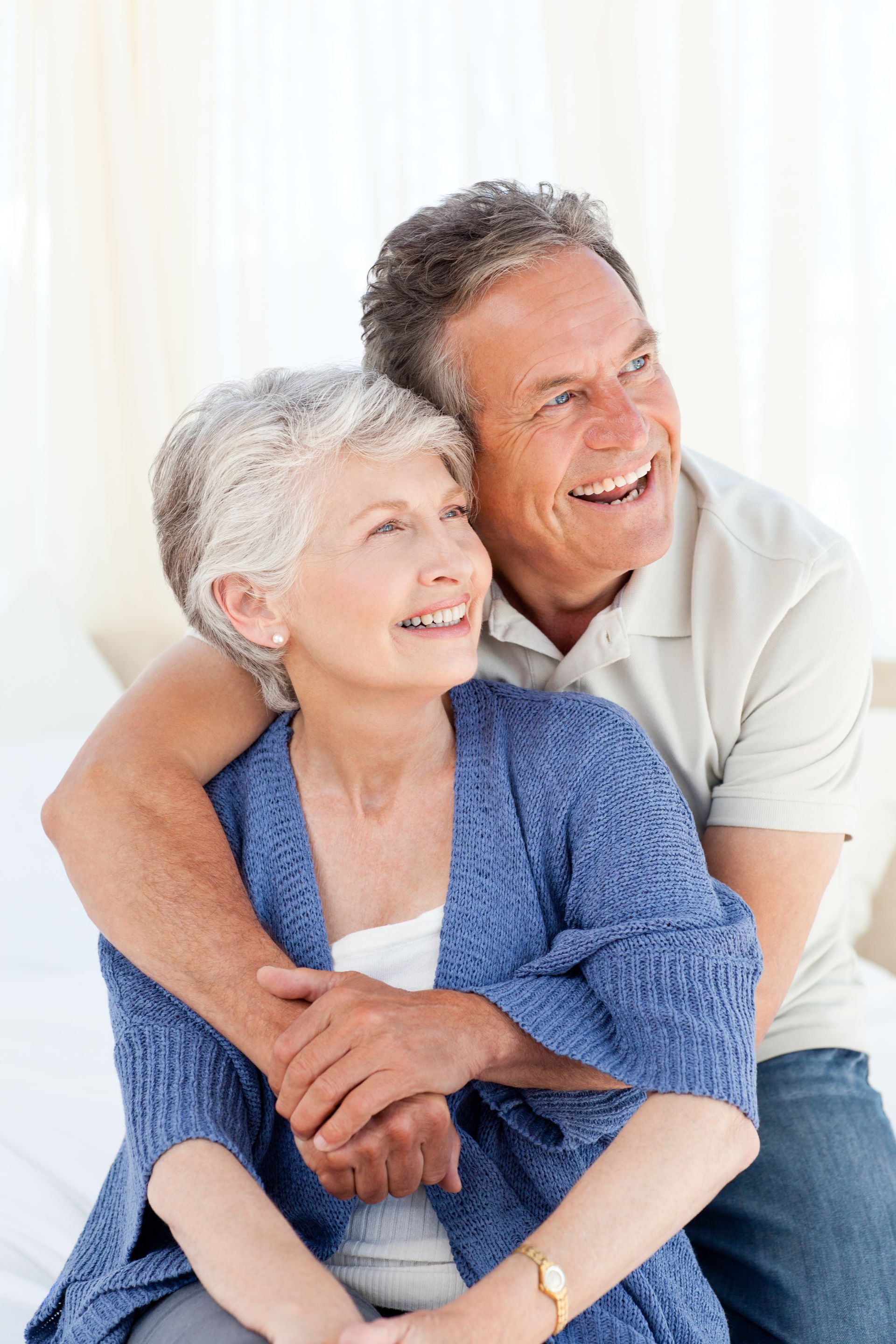 A man is hugging a woman who is sitting on a bed.