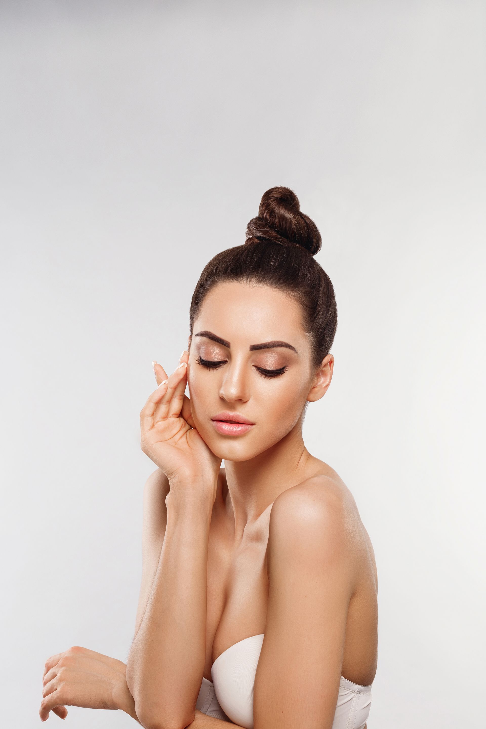 A beautiful young woman with her eyes closed and her hair in a bun.