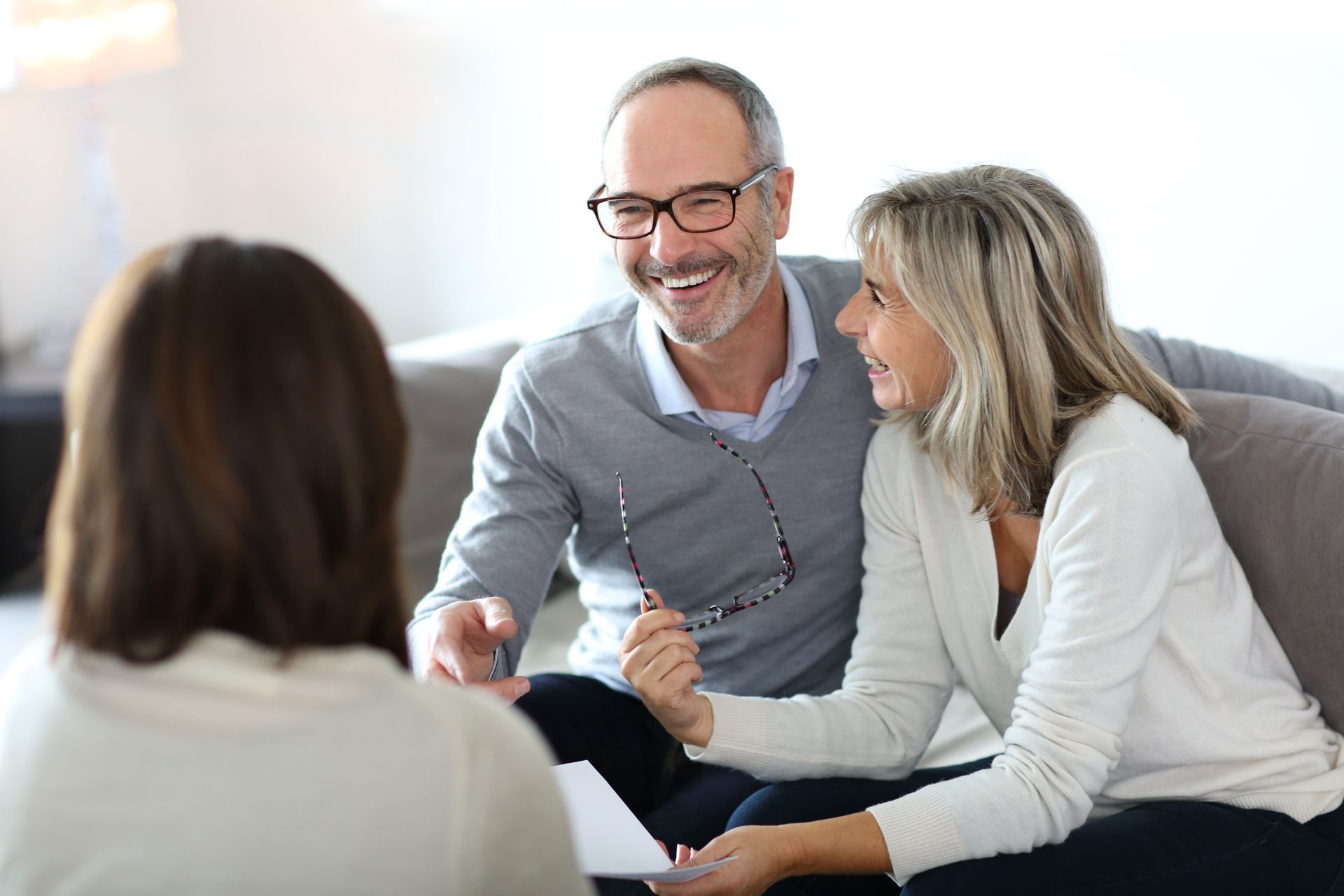 A man and woman are sitting on a couch talking to a woman.