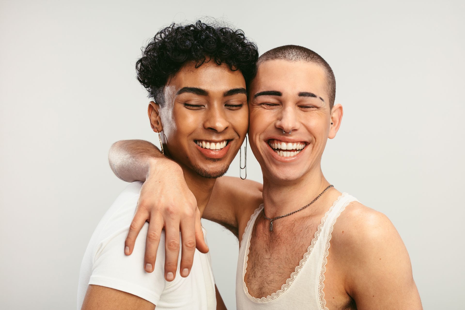 Two young men are hugging each other and smiling for the camera.