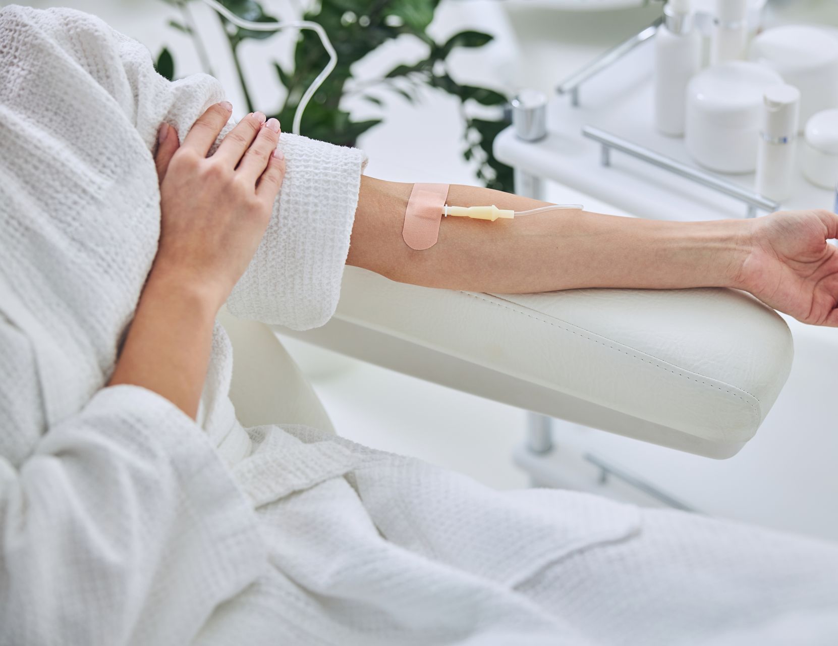 A woman is sitting in a chair with an iv in her arm.