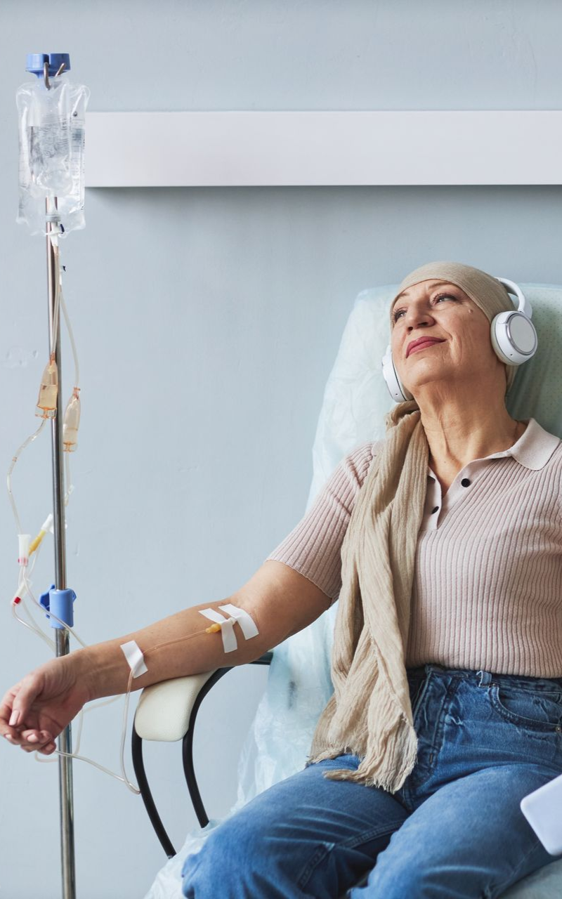 Woman reclining in a chair with IV drip and headphones, resting in a calm clinic setting
