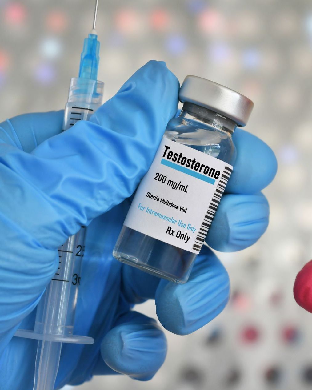 A person is holding a bottle of testosterone and a syringe