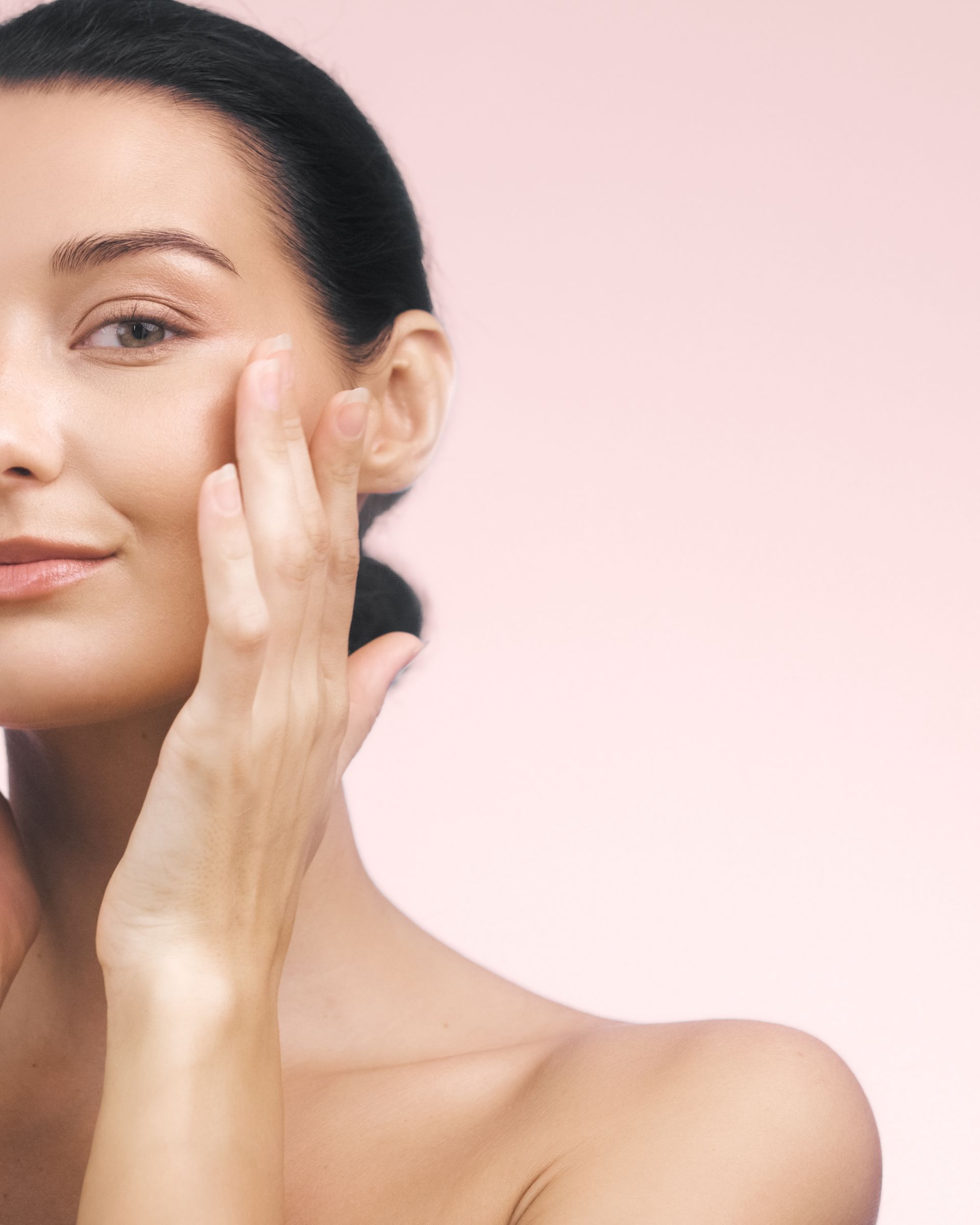 A woman is touching her face with her hand and smiling.