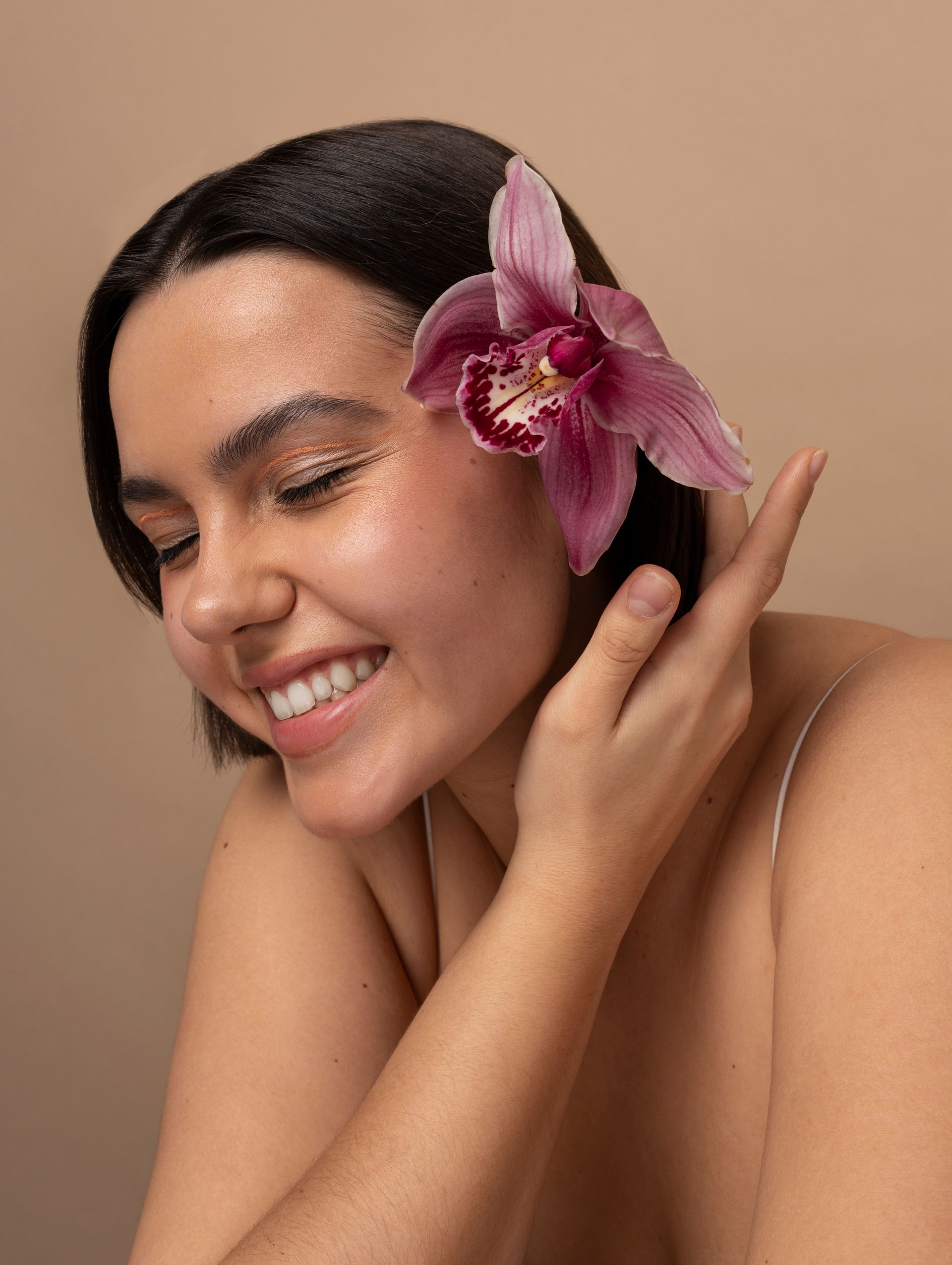 A woman with a flower in her hair is smiling.