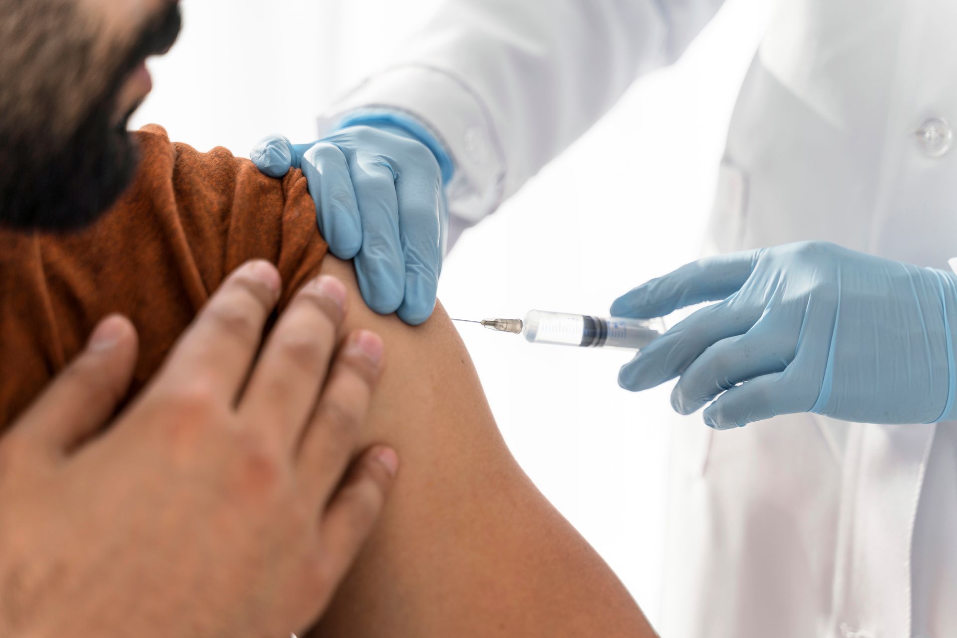 A man is getting an injection in his arm by a doctor.