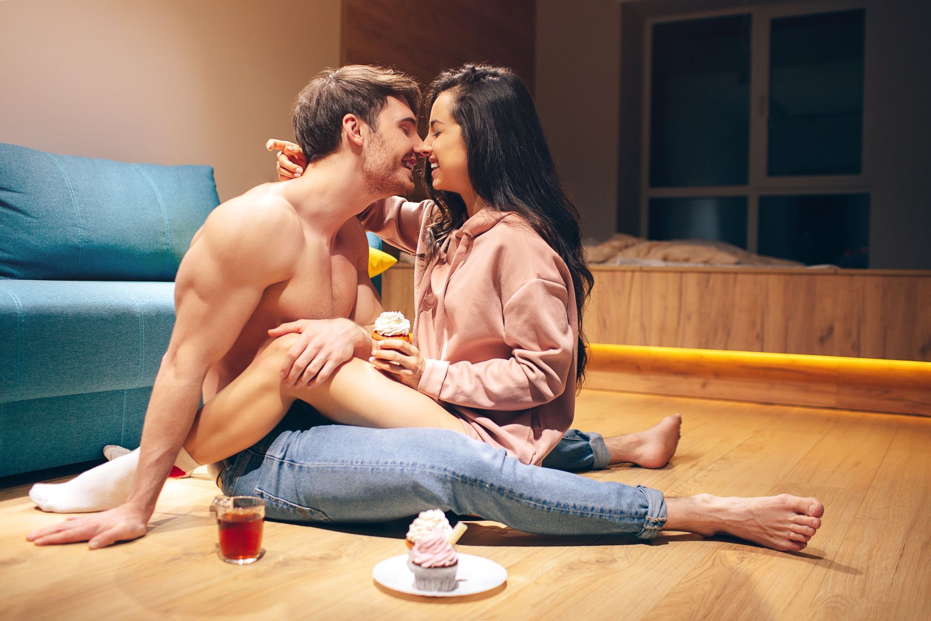 A man and a woman are sitting on the floor kissing.