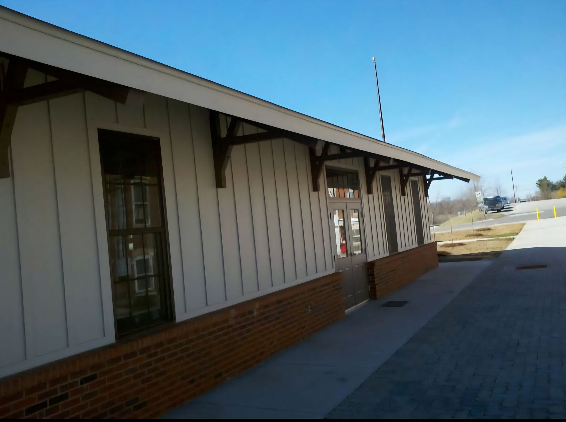 A white building with a brick base, brown trim, and windows.