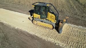 Yellow bulldozer grading a dirt road.