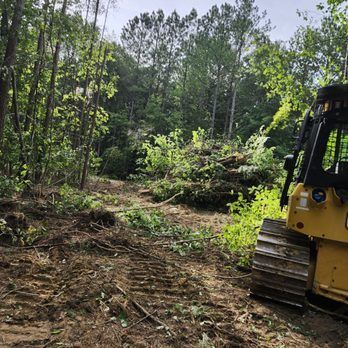 A bulldozer clearing a wooded area, leaving debris behind.