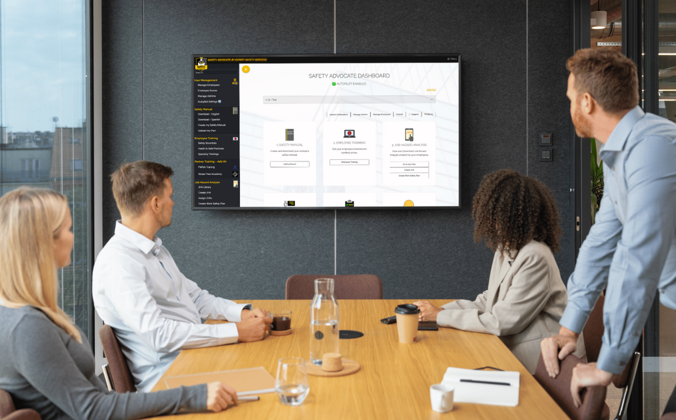 A group of people are sitting around a conference table in front of a flat screen tv.