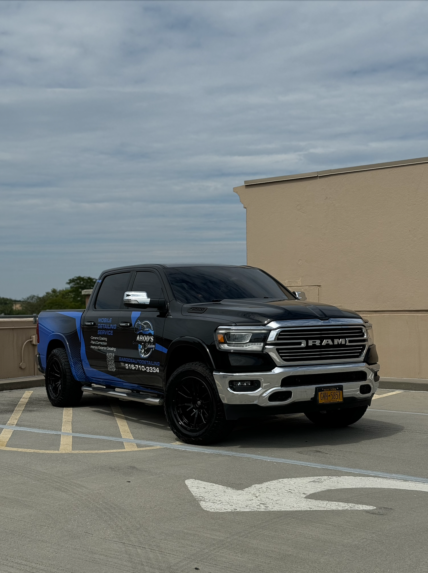 Red Ferrari being washed, with foamy soap on a wheel and a bucket of cleaning supplies. Parked in front of a white garage door on a brick driveway.
