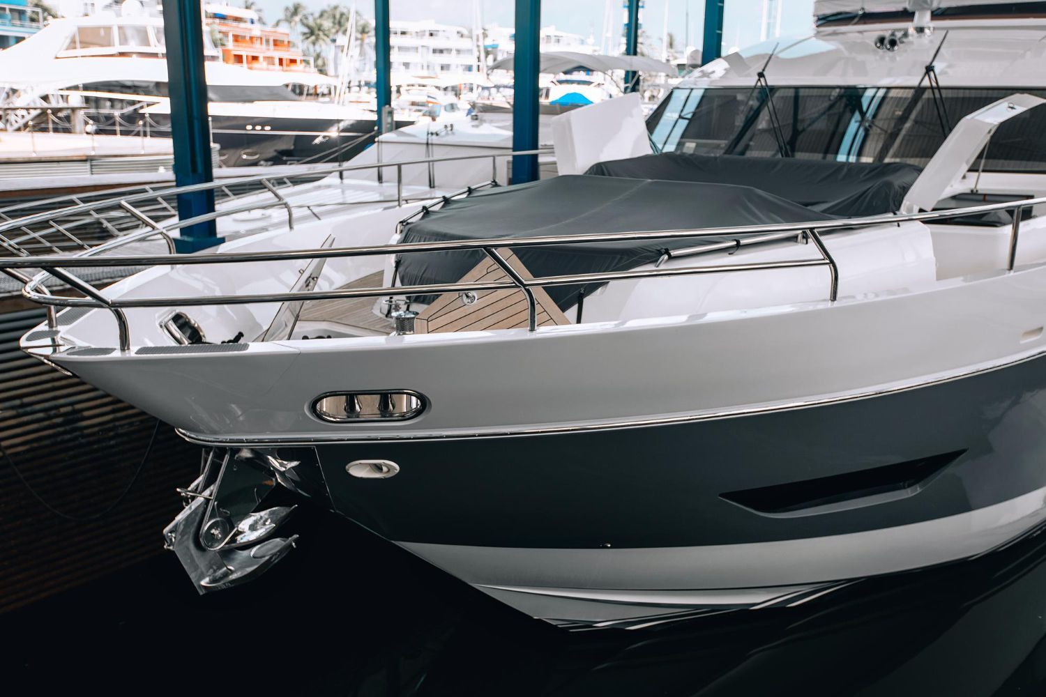White and navy motor yacht at a marina, with stainless steel rails and a dark cover over the front deck.