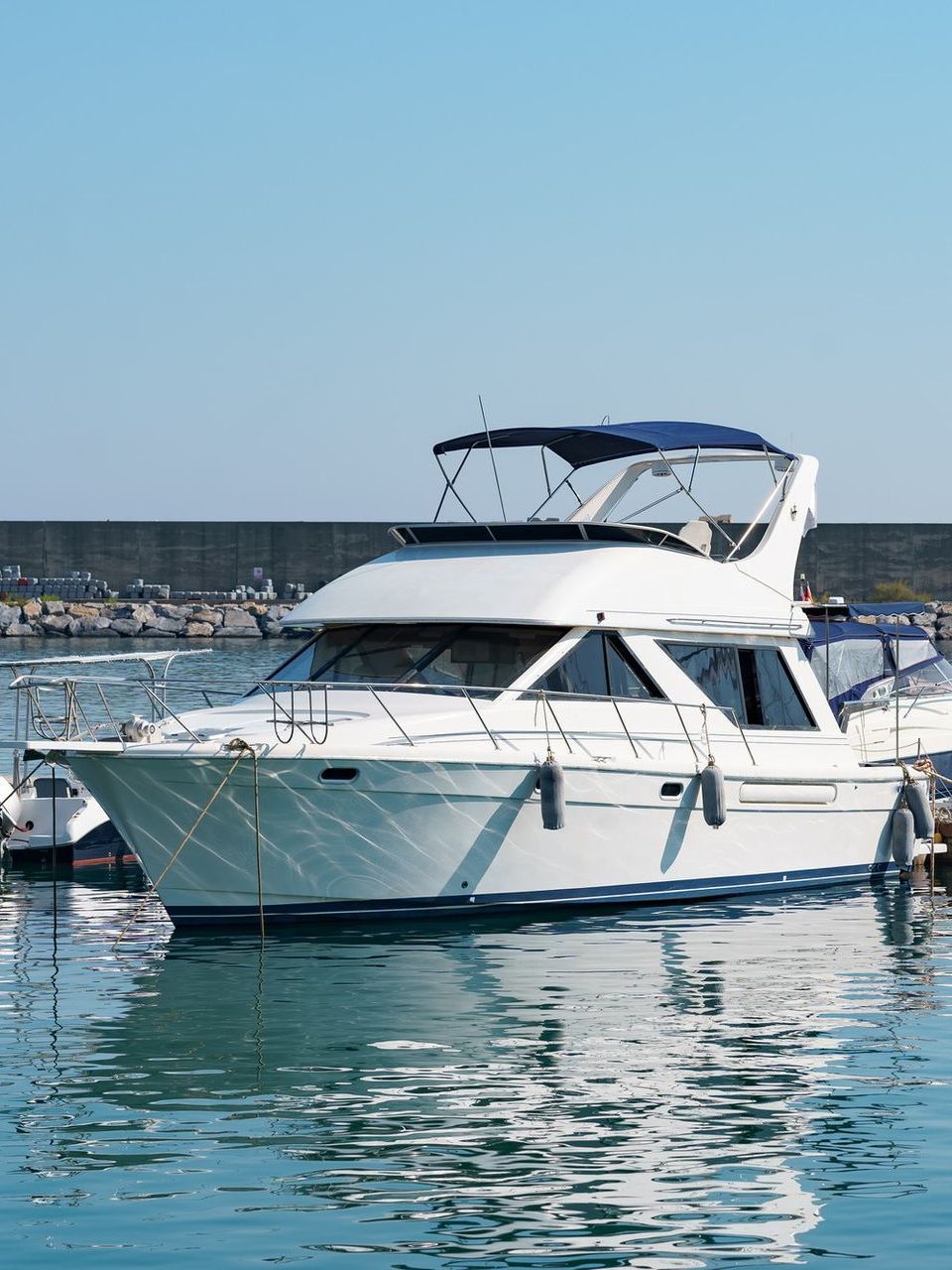 White motor yacht floating in blue water at a dock on a sunny day.