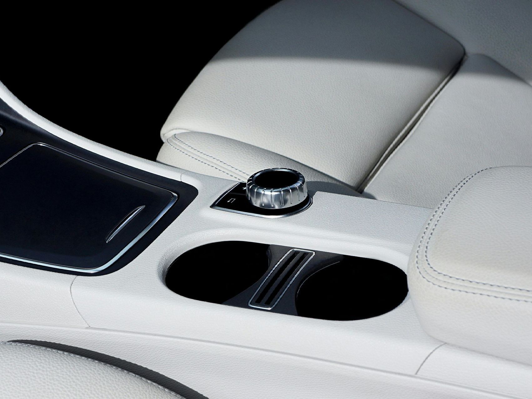 Person wearing a black glove wiping a tan car seat with a white towel, likely cleaning the interior.